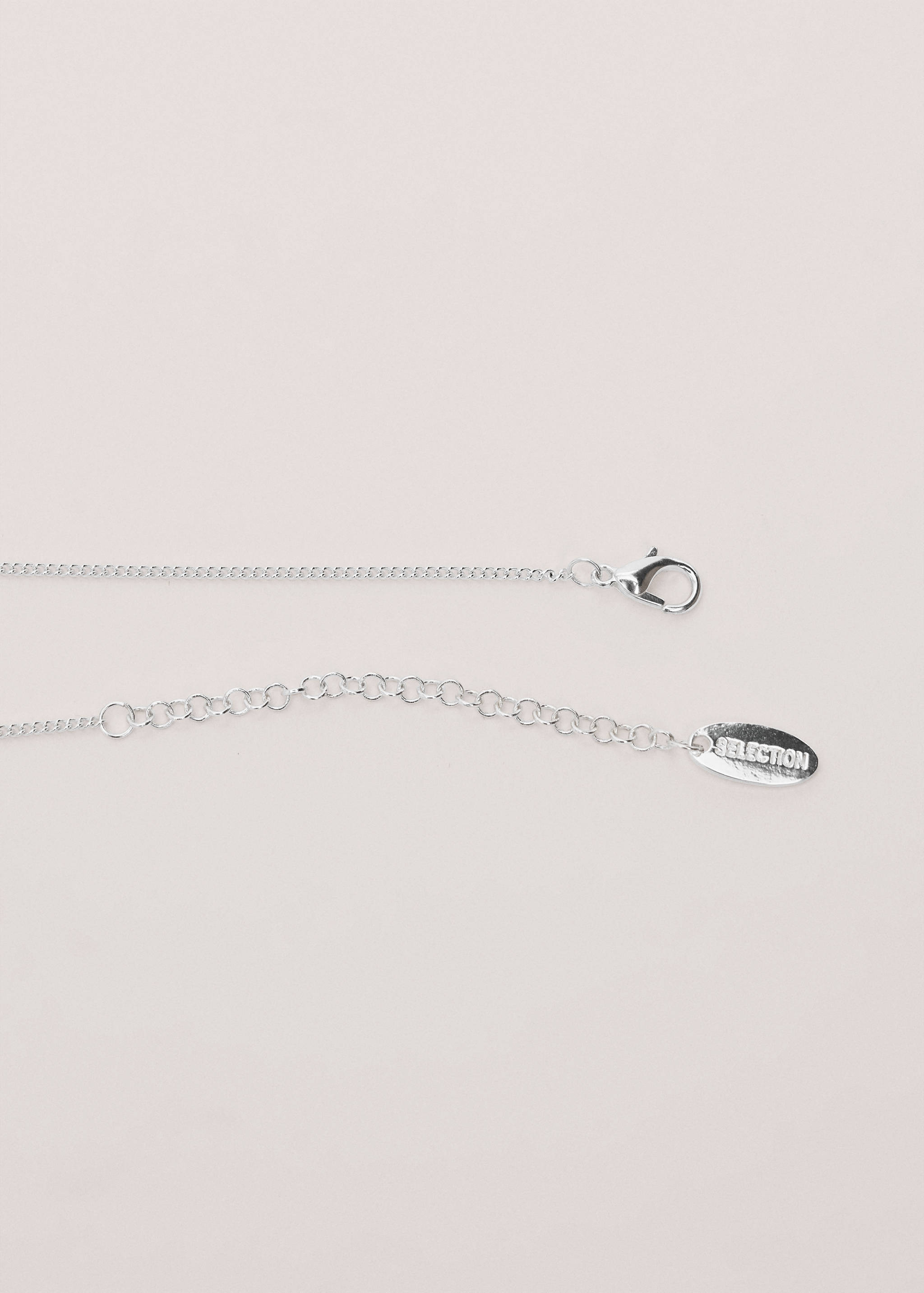Close-up of a silver-coloured chain necklace featuring a lobster clasp, extension chain, and branded tag.
