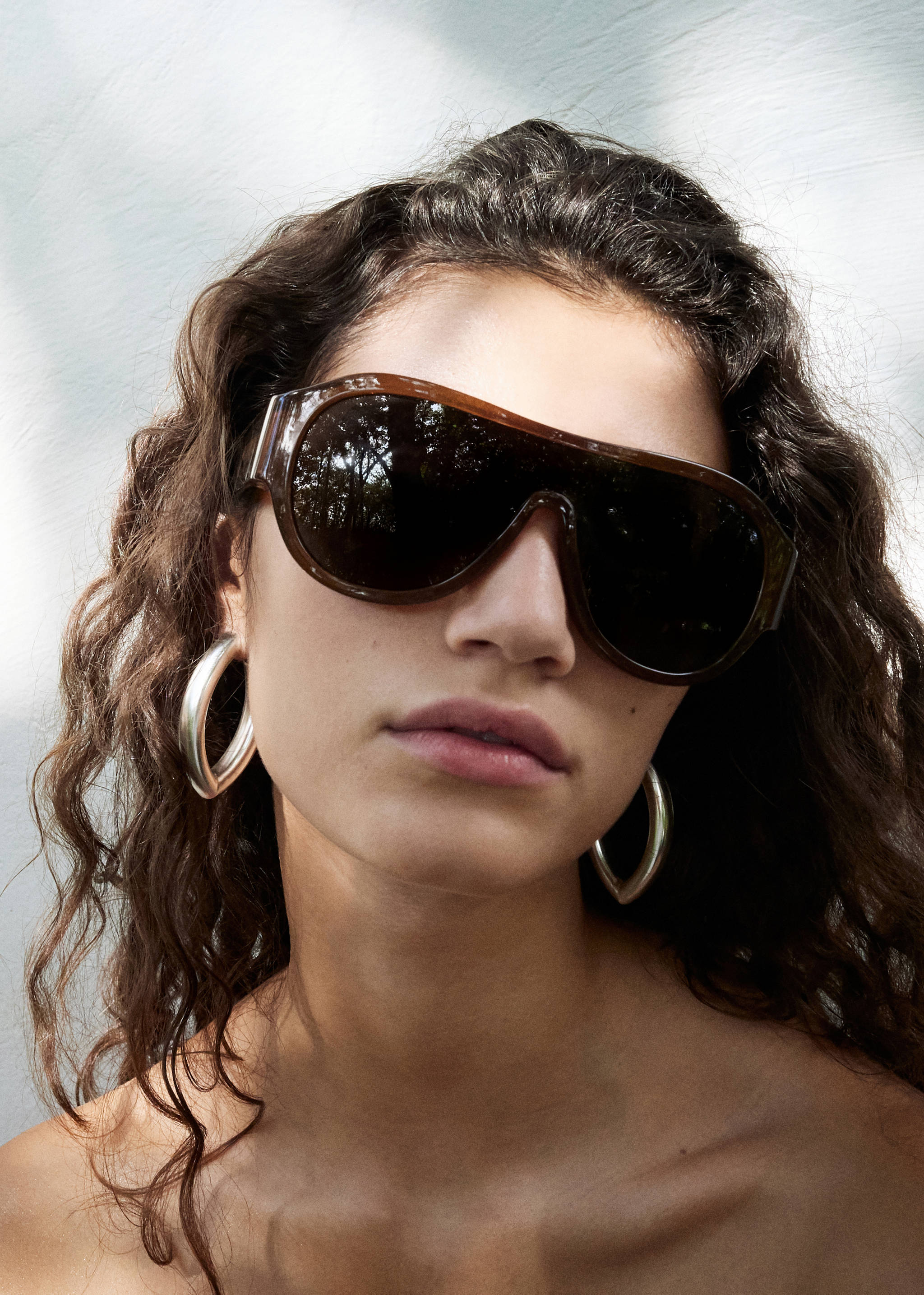 Chunky silver-toned hoop earrings worn with oversized tortoiseshell sunglasses.