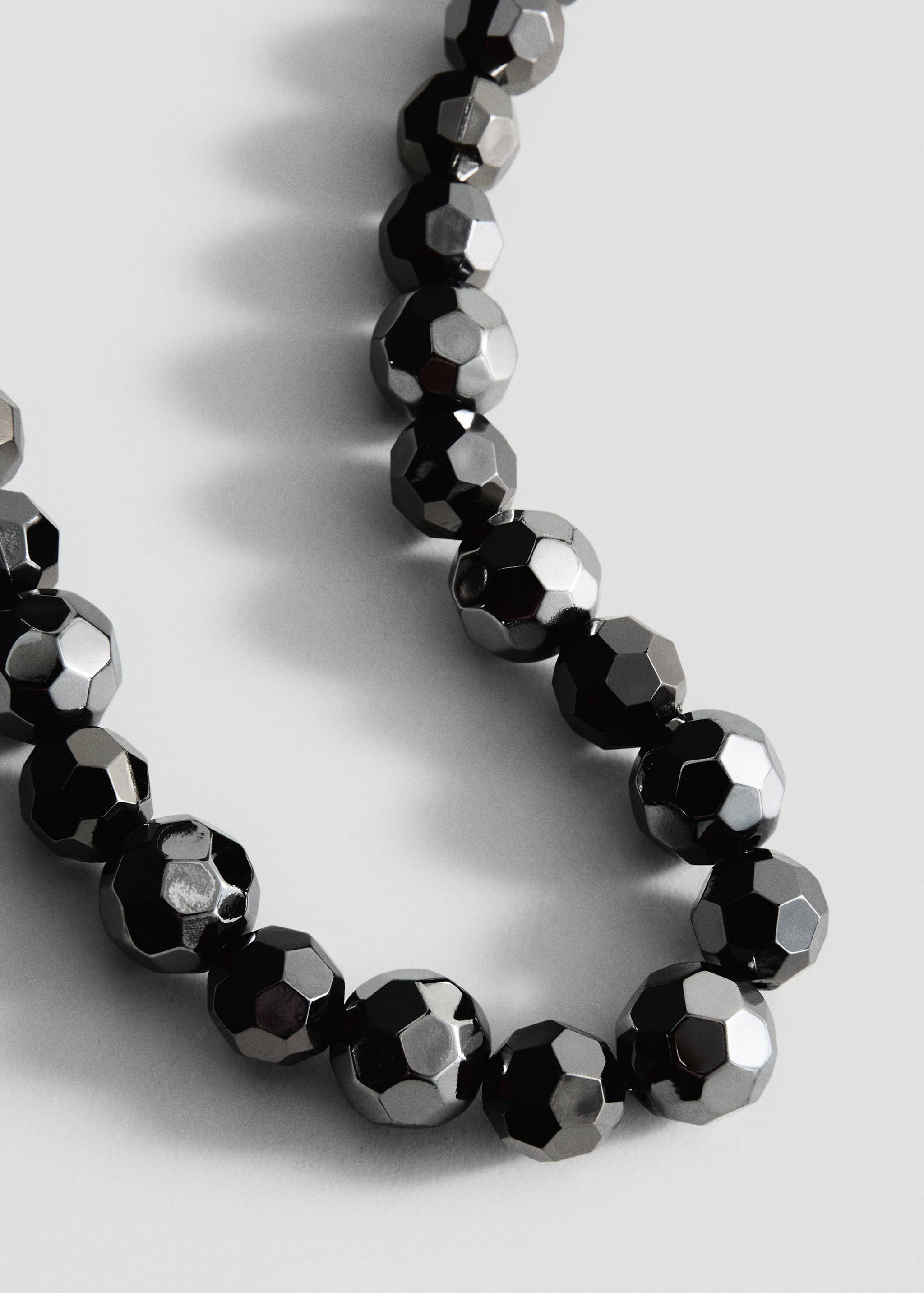 Close-up of a dark metallic faceted bead necklace.