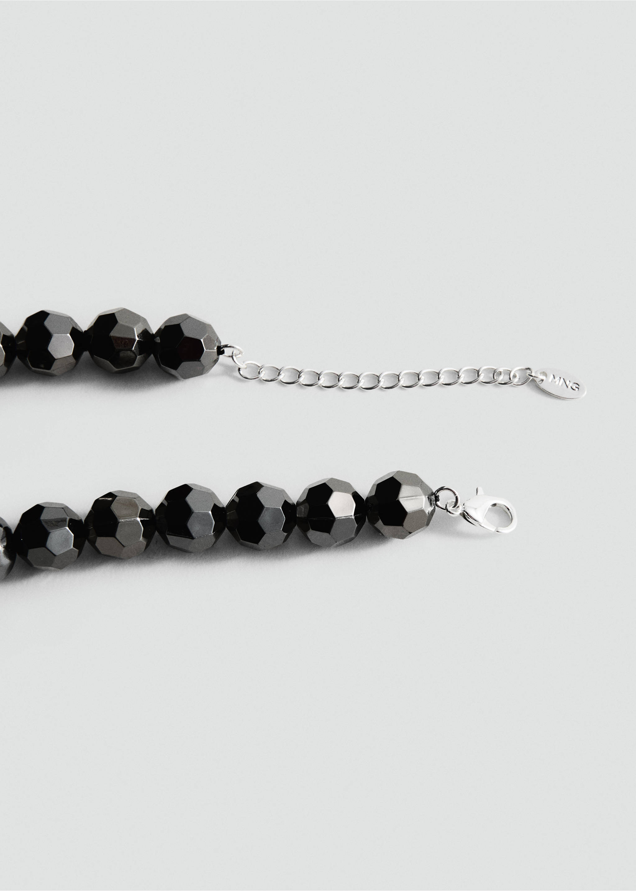 Close-up of a faceted dark metallic beaded collar with a silver-toned chain extender., Silver. Ref: 27021228-00.