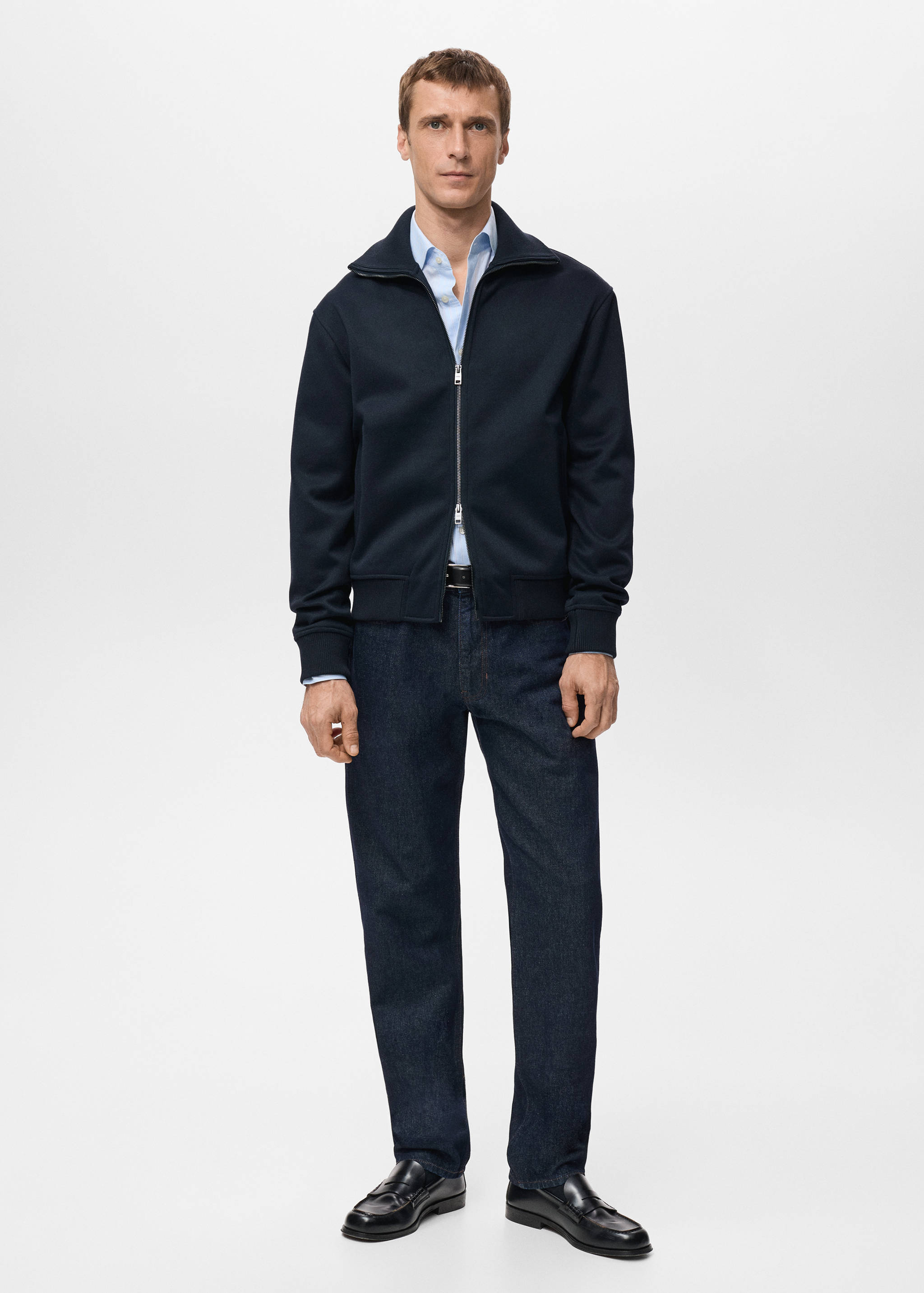 Navy blue zip-up sweatshirt with a high collar worn over a light blue shirt.