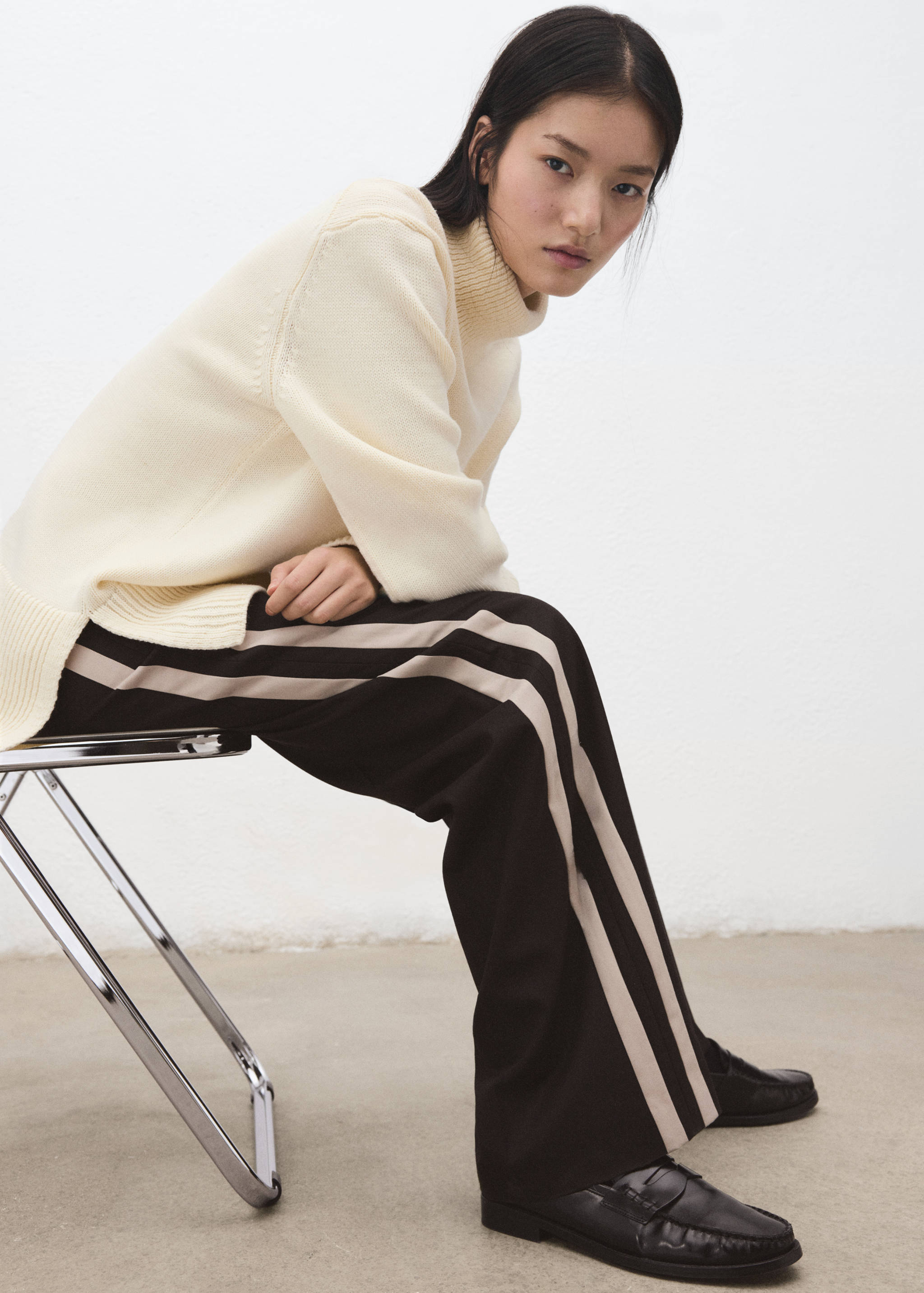 Black trousers with pale beige side stripes and a straight fit.