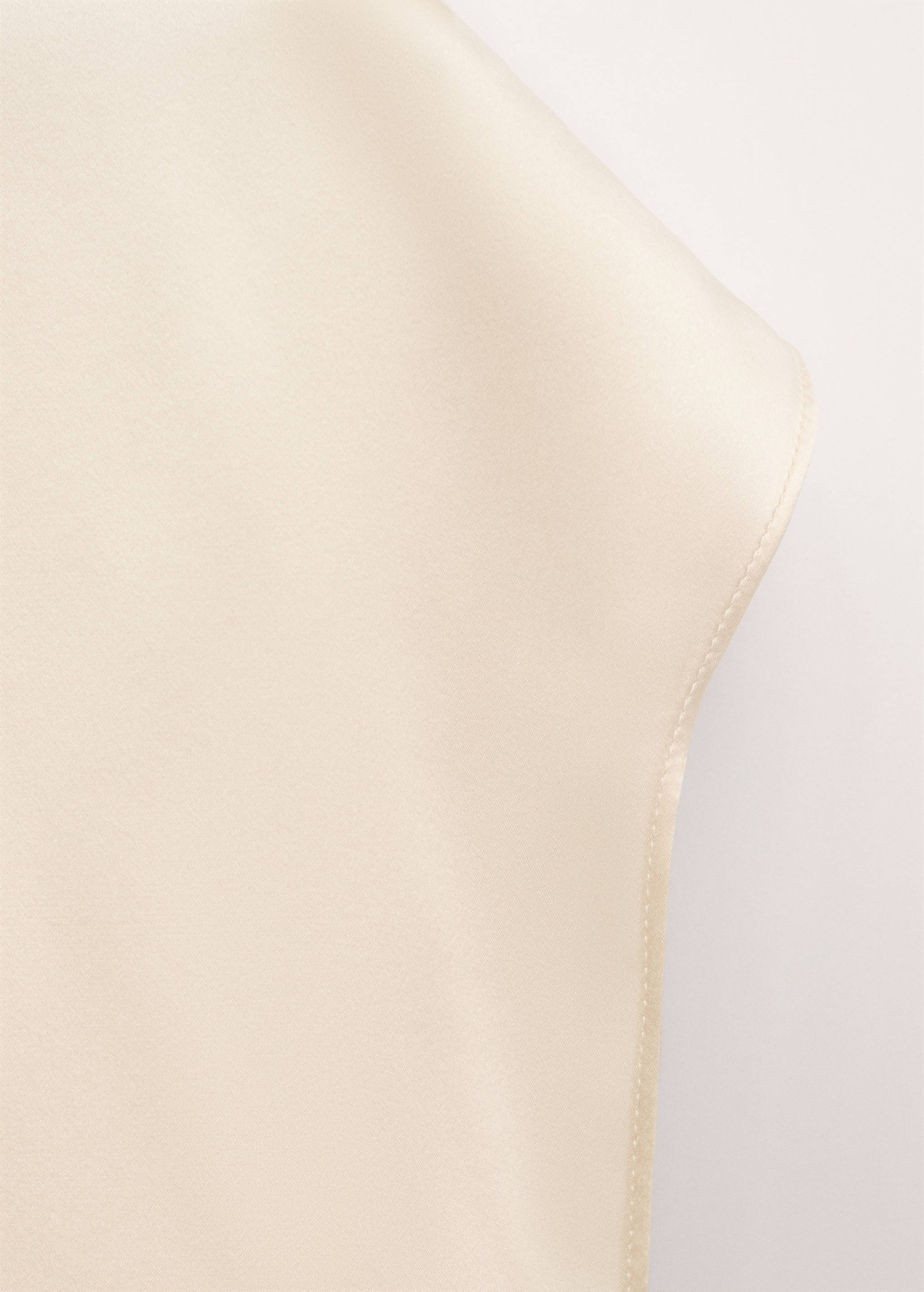 Close-up of a cream satin blouse detail.