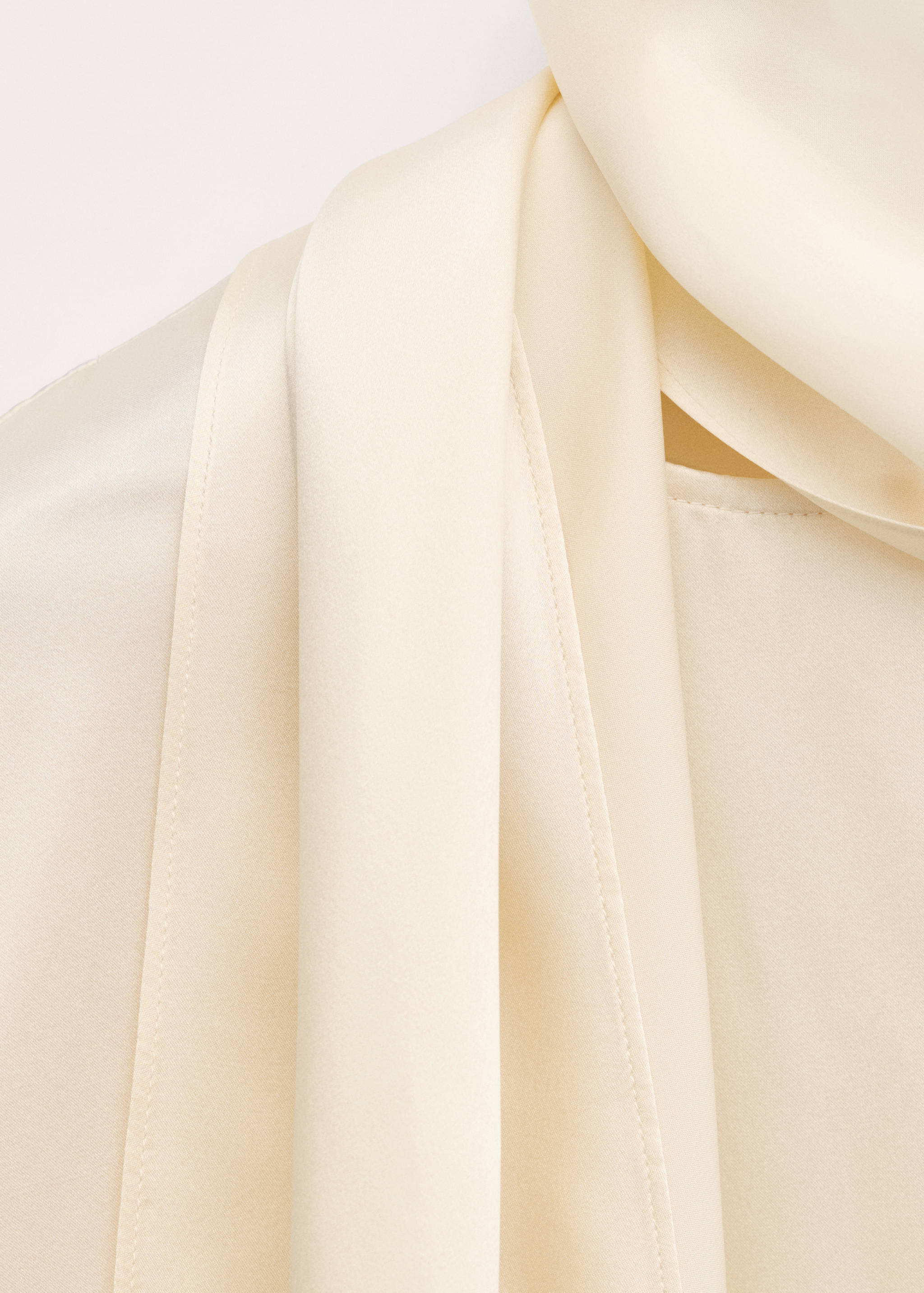 Close-up of cream blouse fabric showing smooth texture and drape.