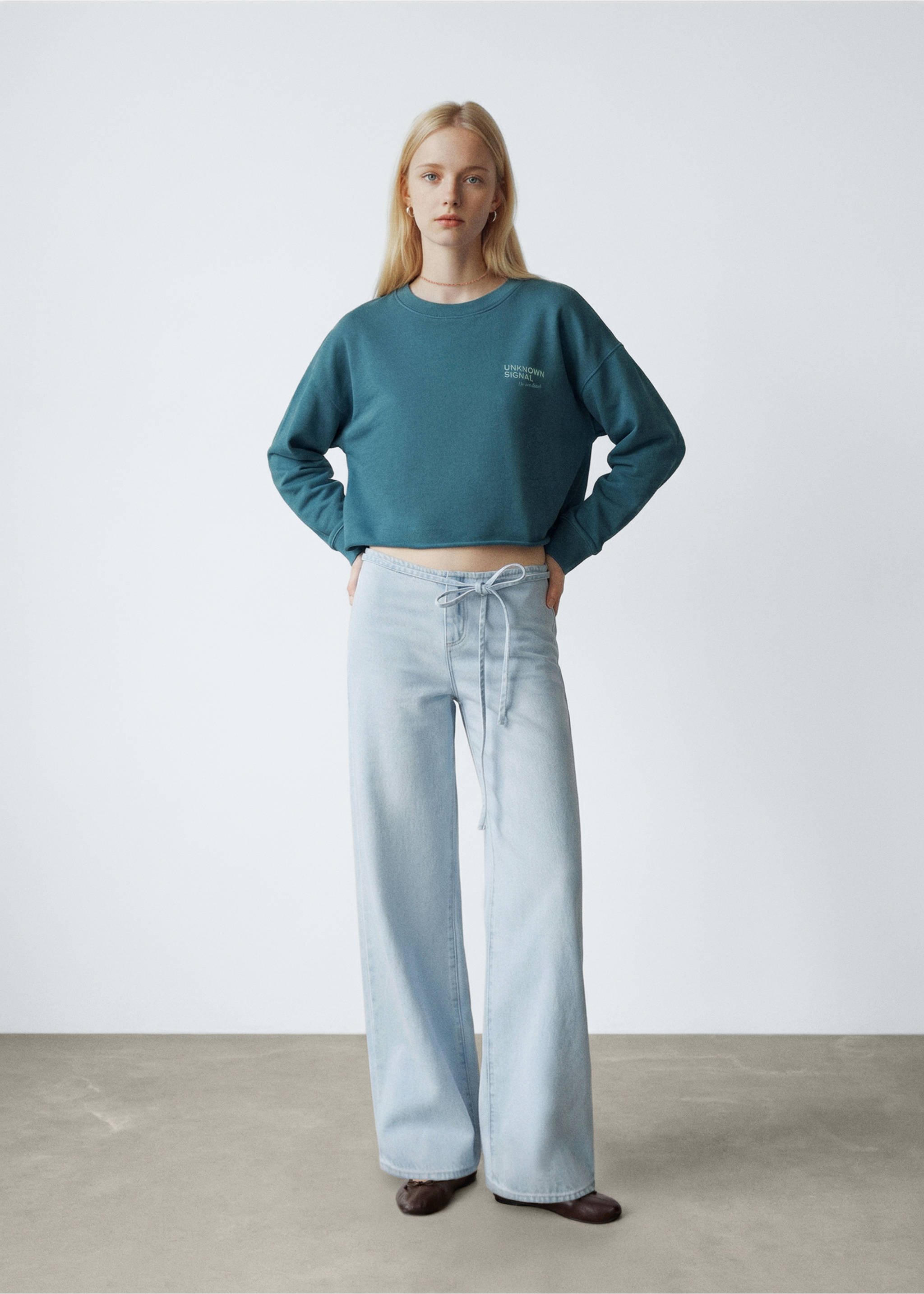 Teal cropped crew-neck sweatshirt with text print, worn with light blue drawstring denim trousers., Petrol Blue. Ref: 27024778-00.