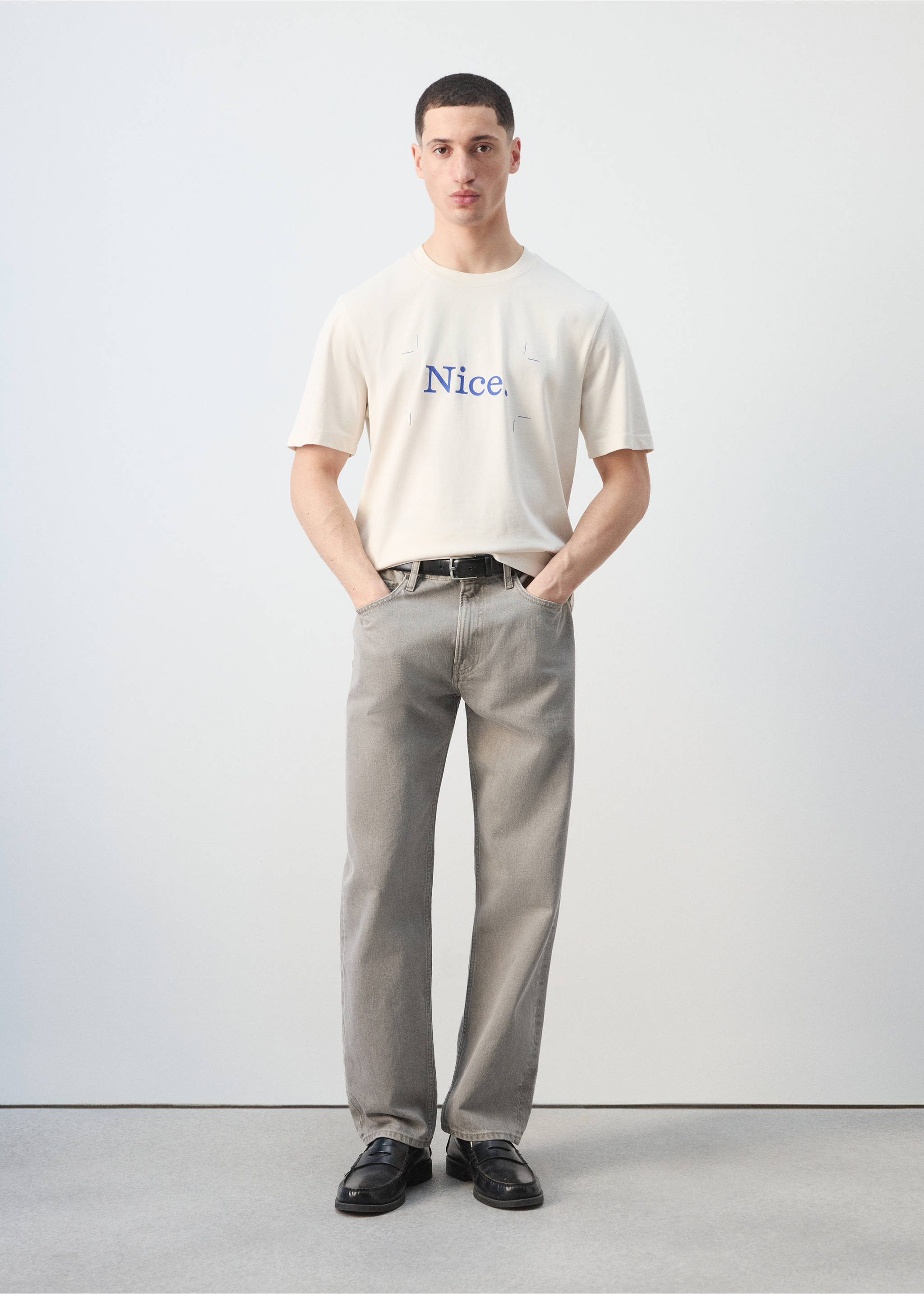 Off-white short-sleeved t-shirt with blue chest text, worn with grey trousers., Off White. Ref: 27025993-00.