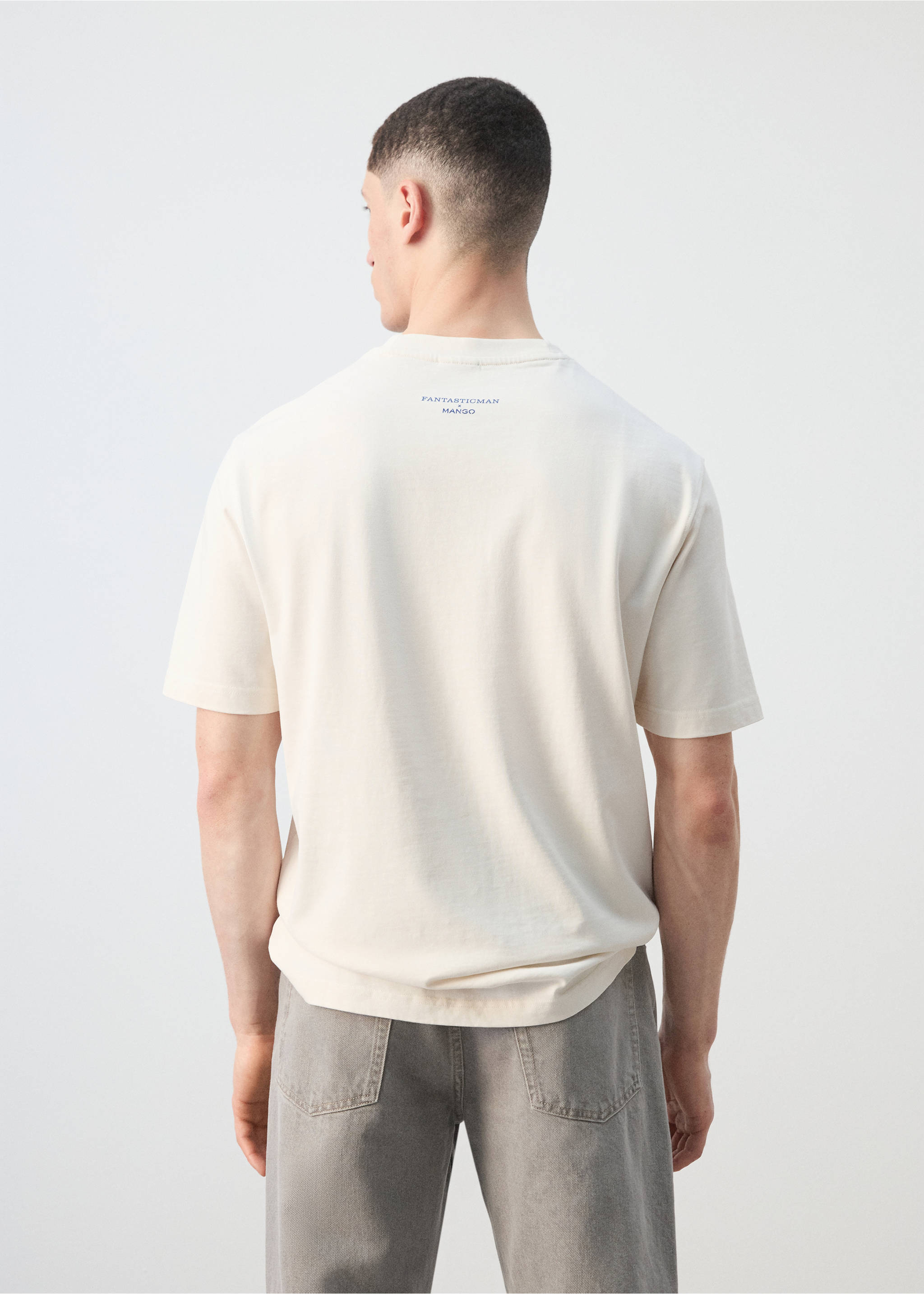 Back view of an off-white short-sleeved t-shirt with a back neck print, paired with grey trousers., Off White. Ref: 27025993-00.