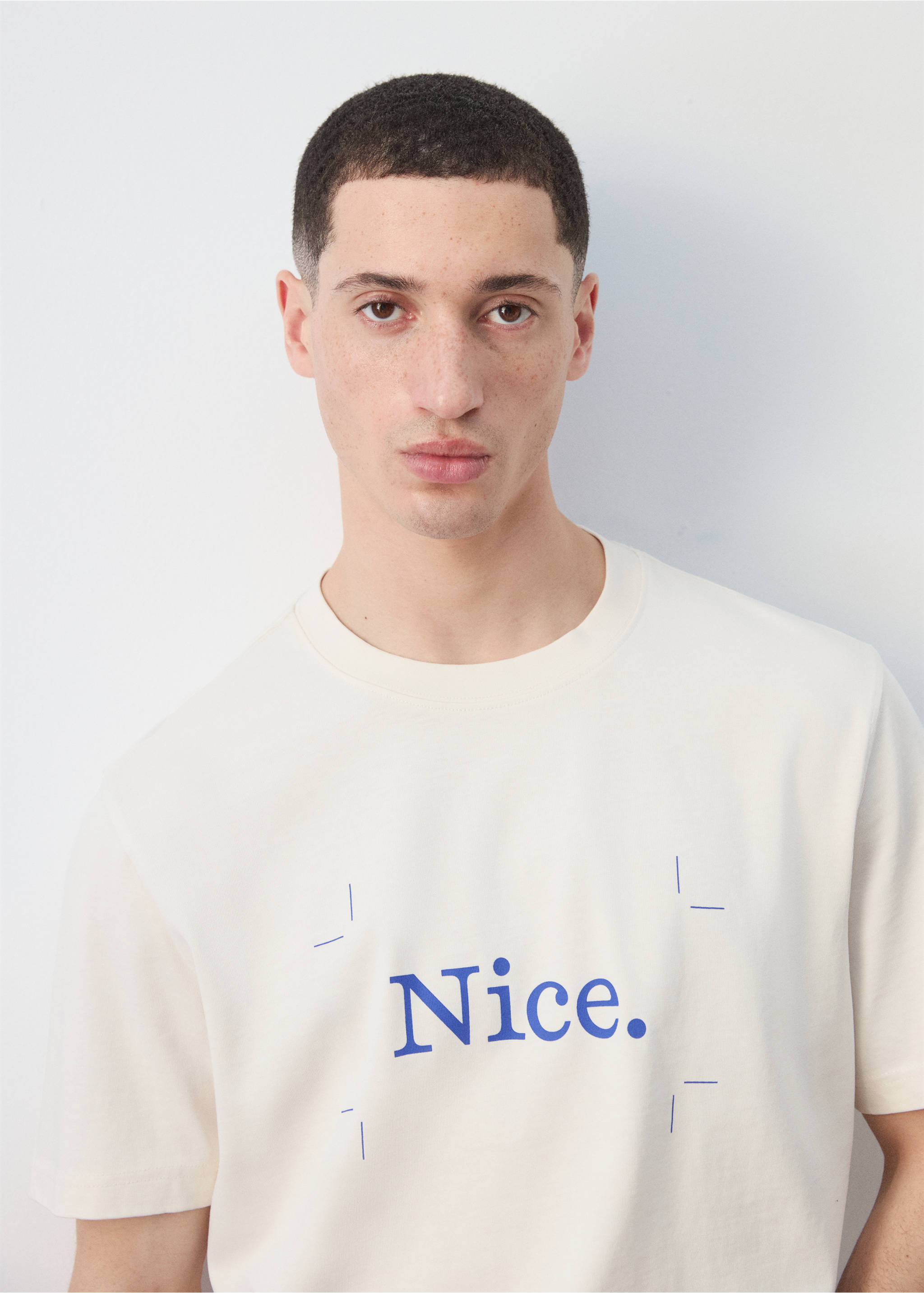 Close-up of a cream t-shirt with blue 'Nice.' print and crew neck., Off White. Ref: 27025993-00.