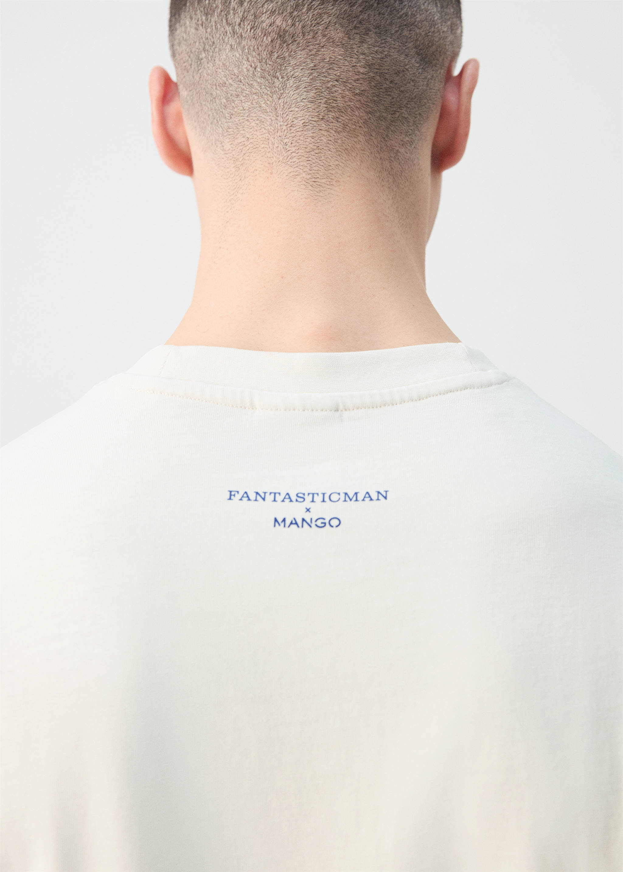 Back detail of a light t-shirt with a blue logo print below the collar.