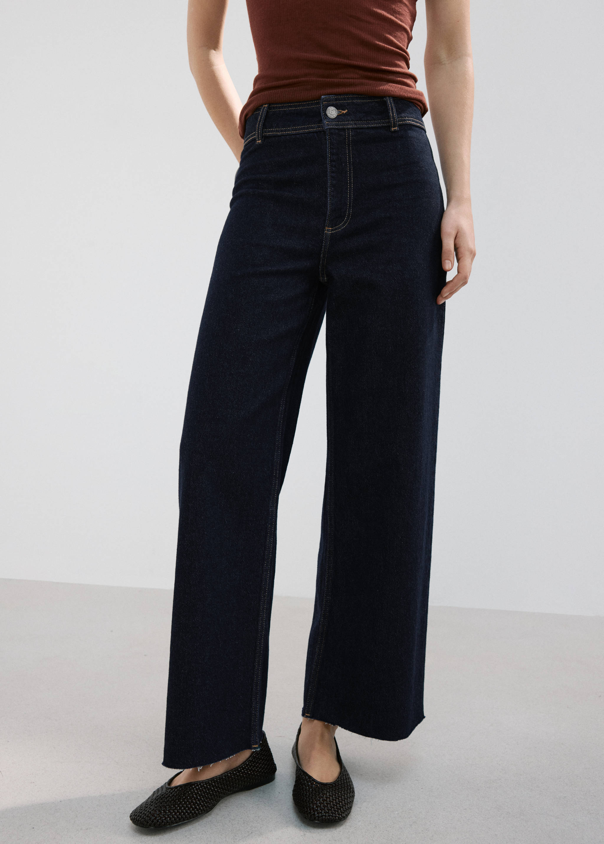 Dark blue high-waisted wide-leg denim trousers with raw hems.