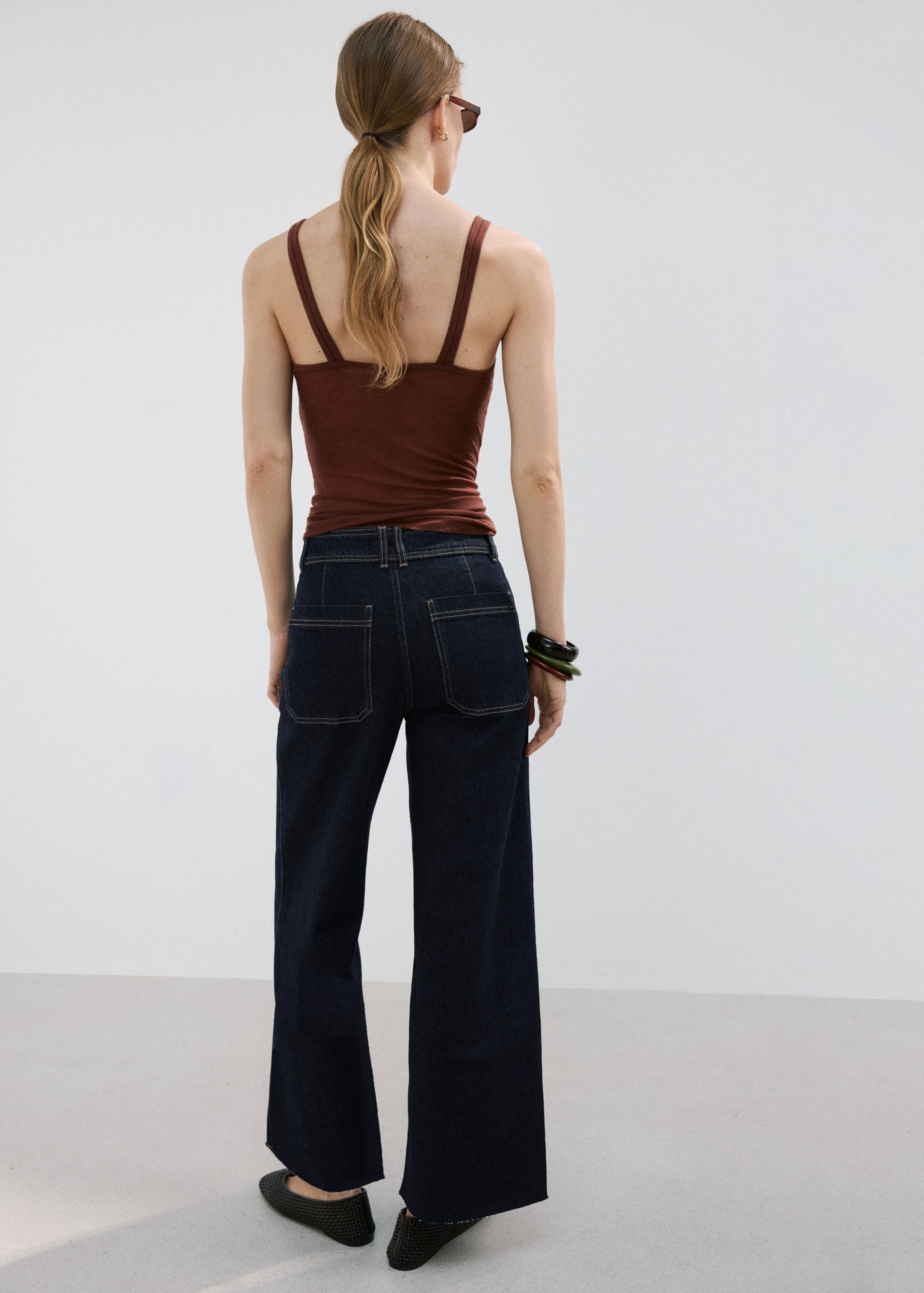Dark wash wide-leg denim trousers with rear patch pockets, seen from the back