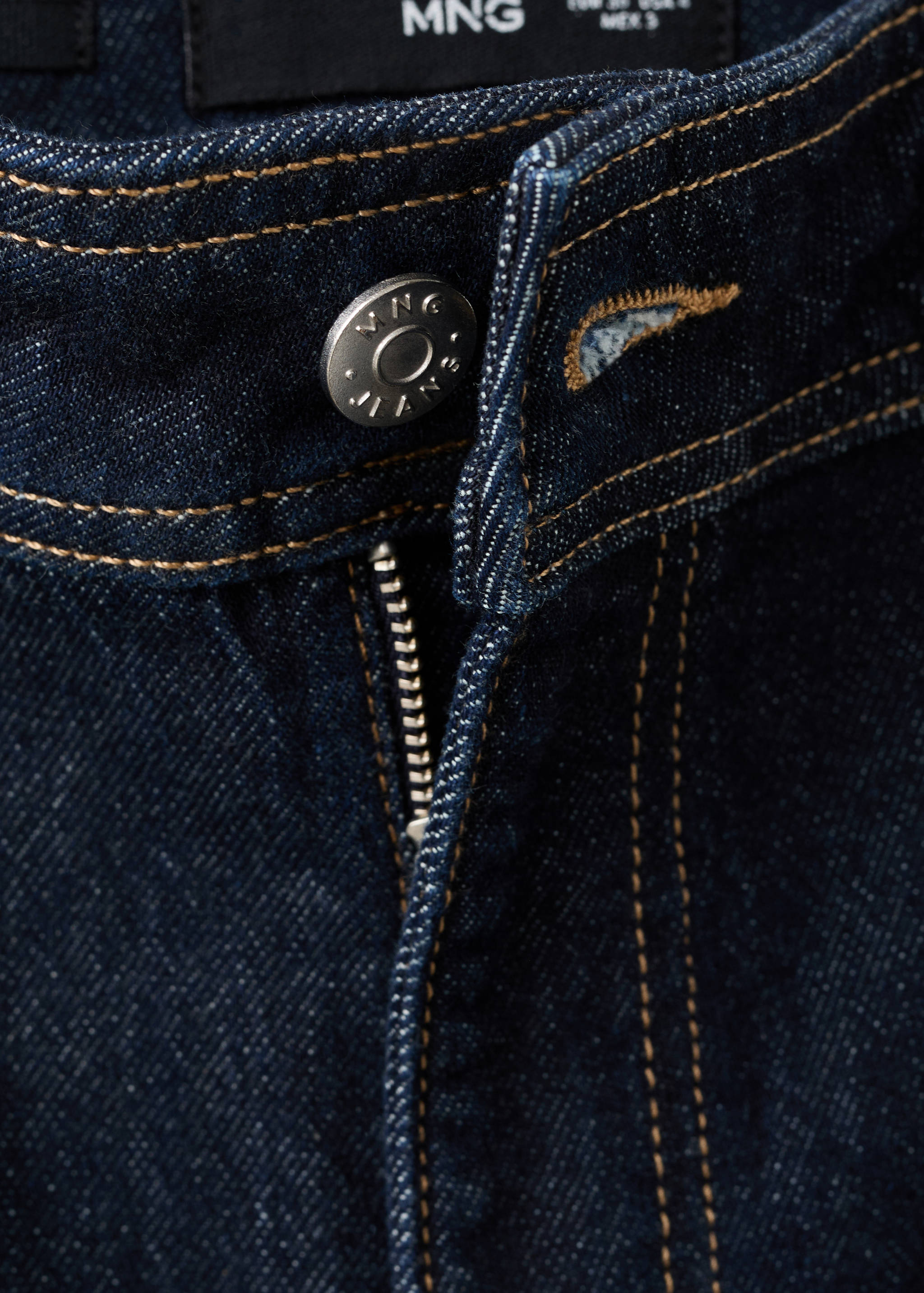 Close-up of dark blue denim trousers featuring contrast topstitching and a metal button.