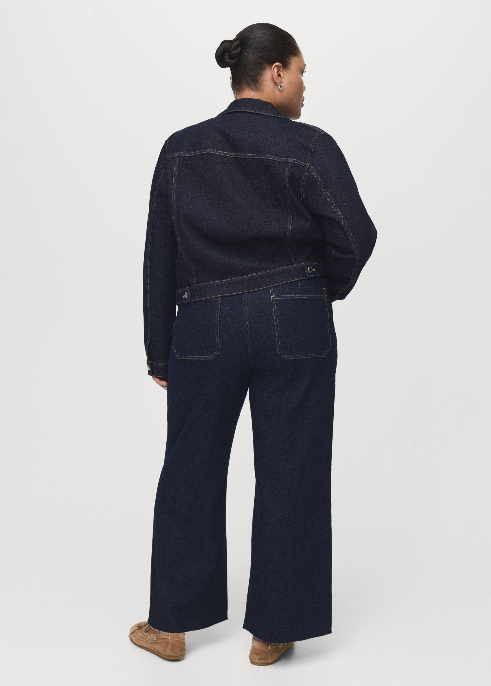 Back view of a dark blue denim jacket with contrast topstitching.