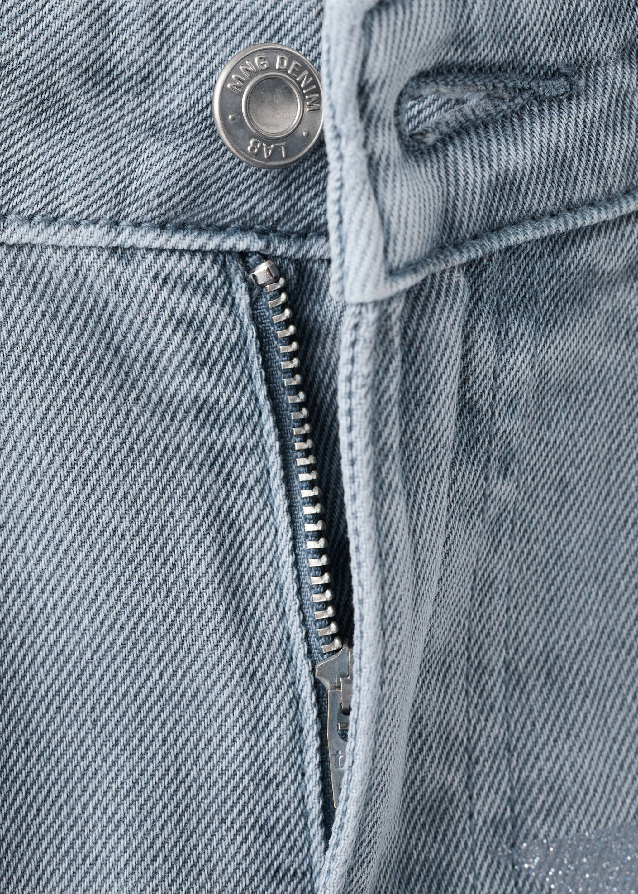 Close-up of light-wash blue denim trousers showing the button and zip fly., Blue. Ref: 27031289-00.