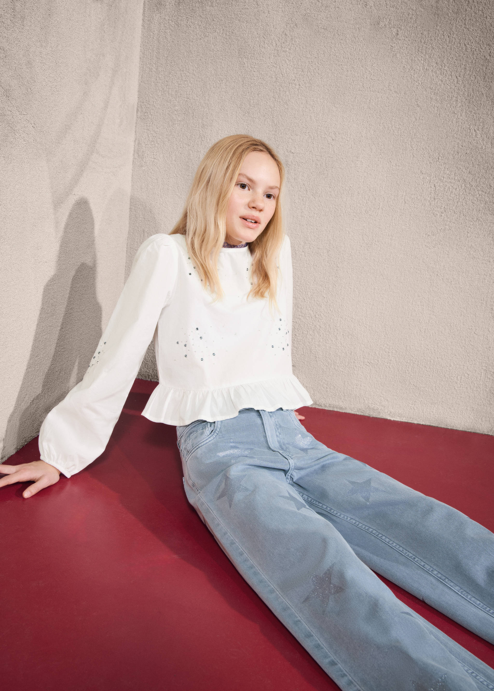 Light blue jeans with a star print pattern worn by a seated young girl.