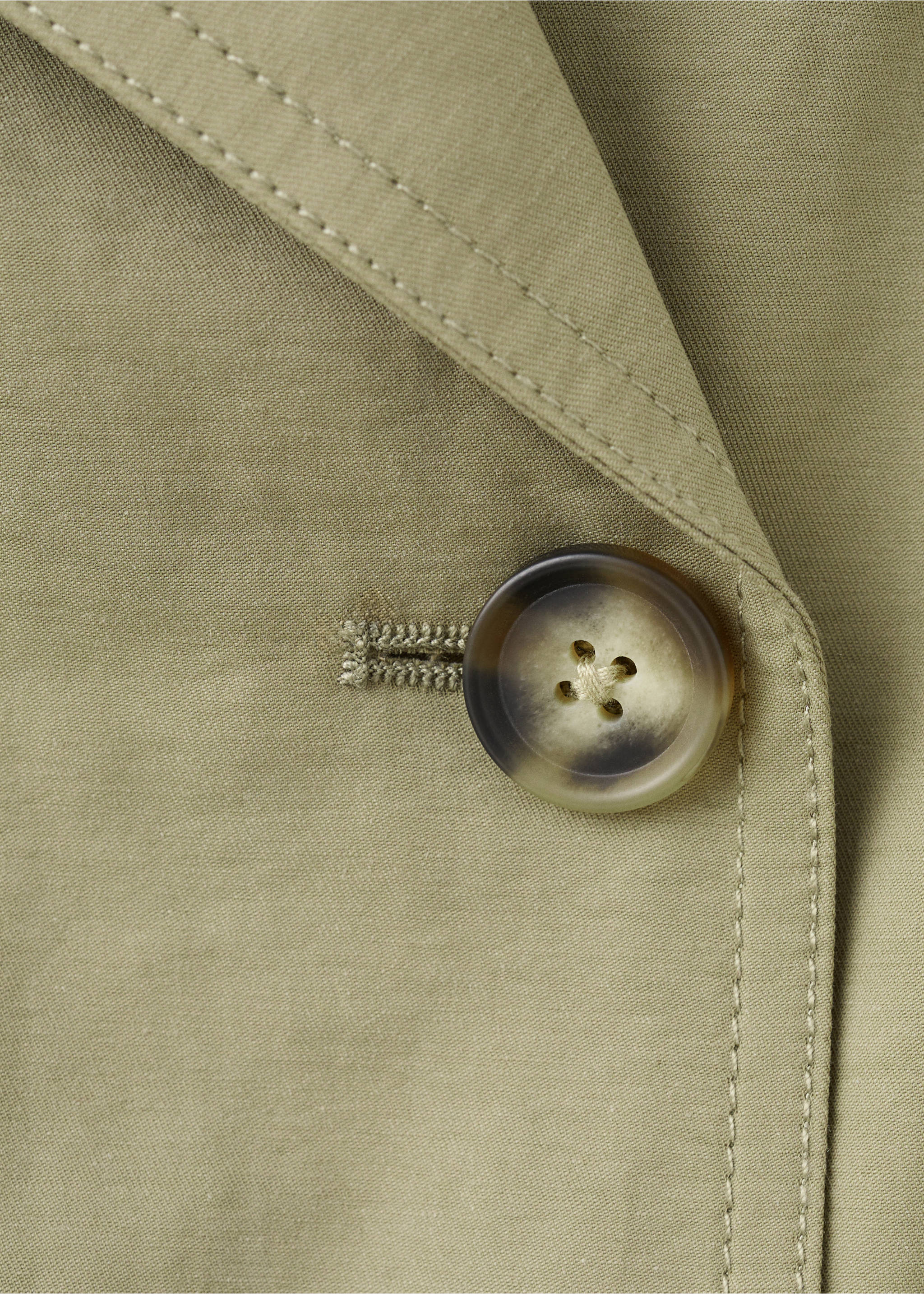 Close-up of a khaki green trench coat showing fabric texture and a tortoiseshell button., Khaki. Ref: 27034057-00.