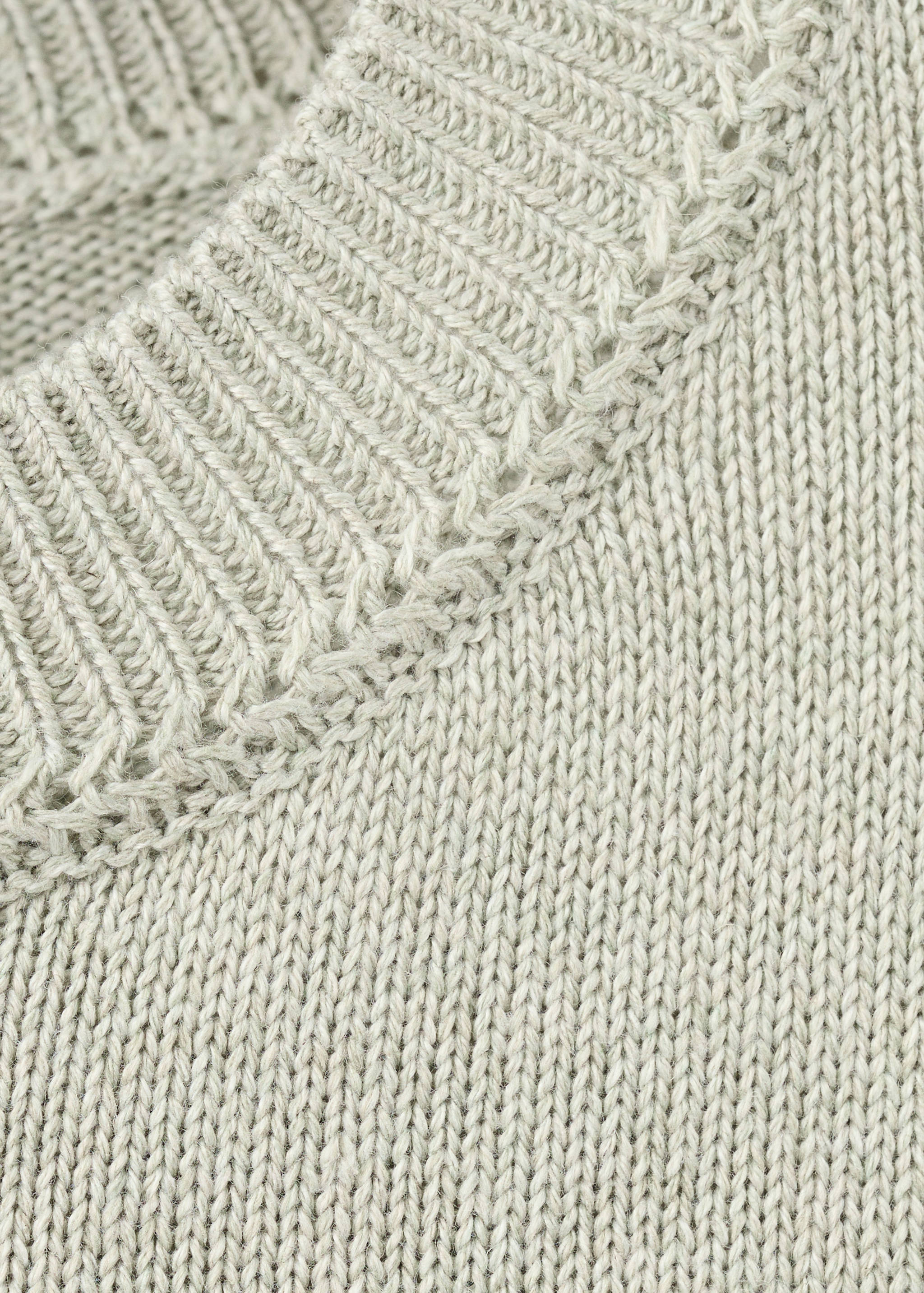 Close-up of light grey knitted jersey showing the textured knit and ribbed collar.