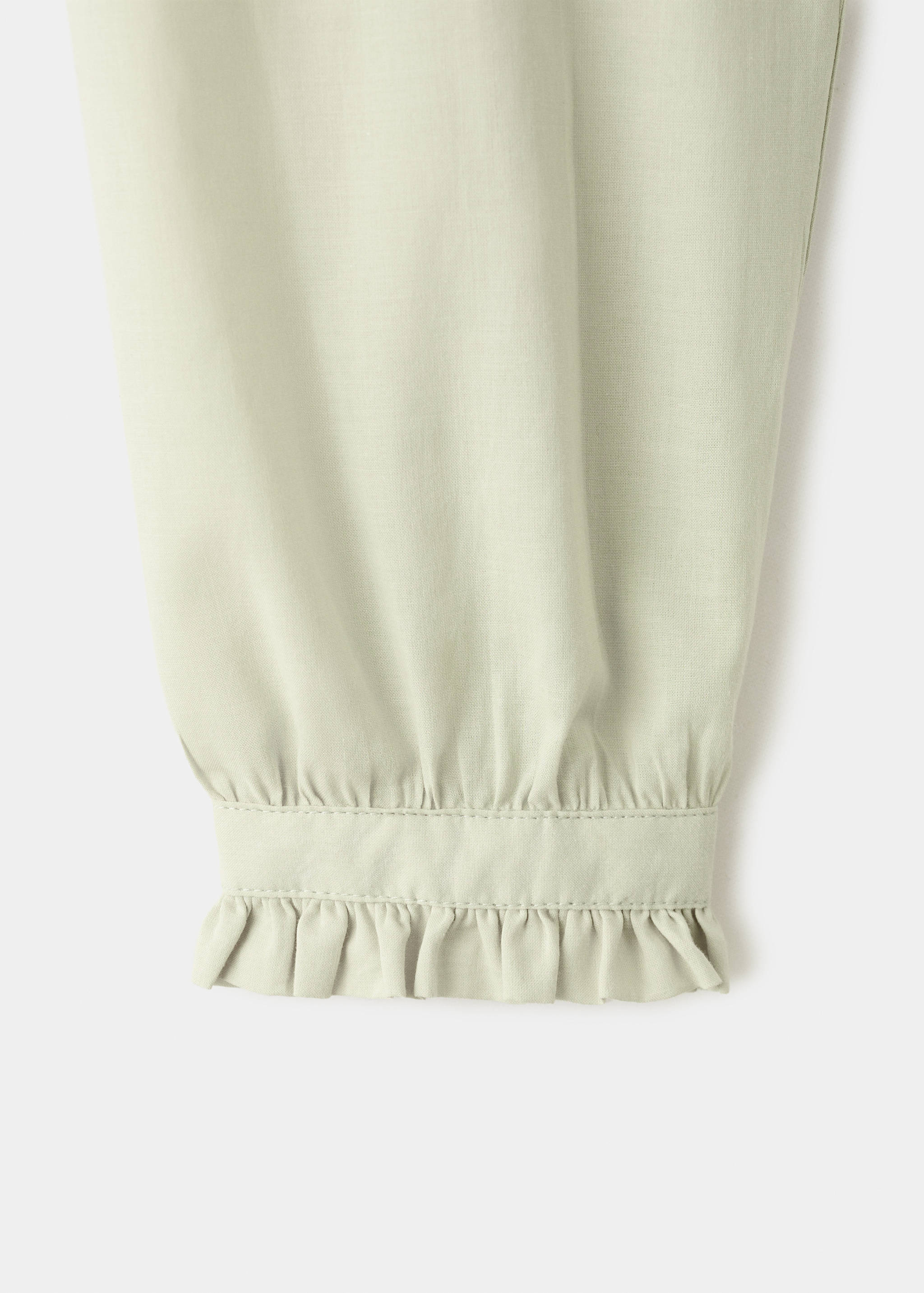 Close-up of a pale green jersey sleeve with a ruffled cuff detail.