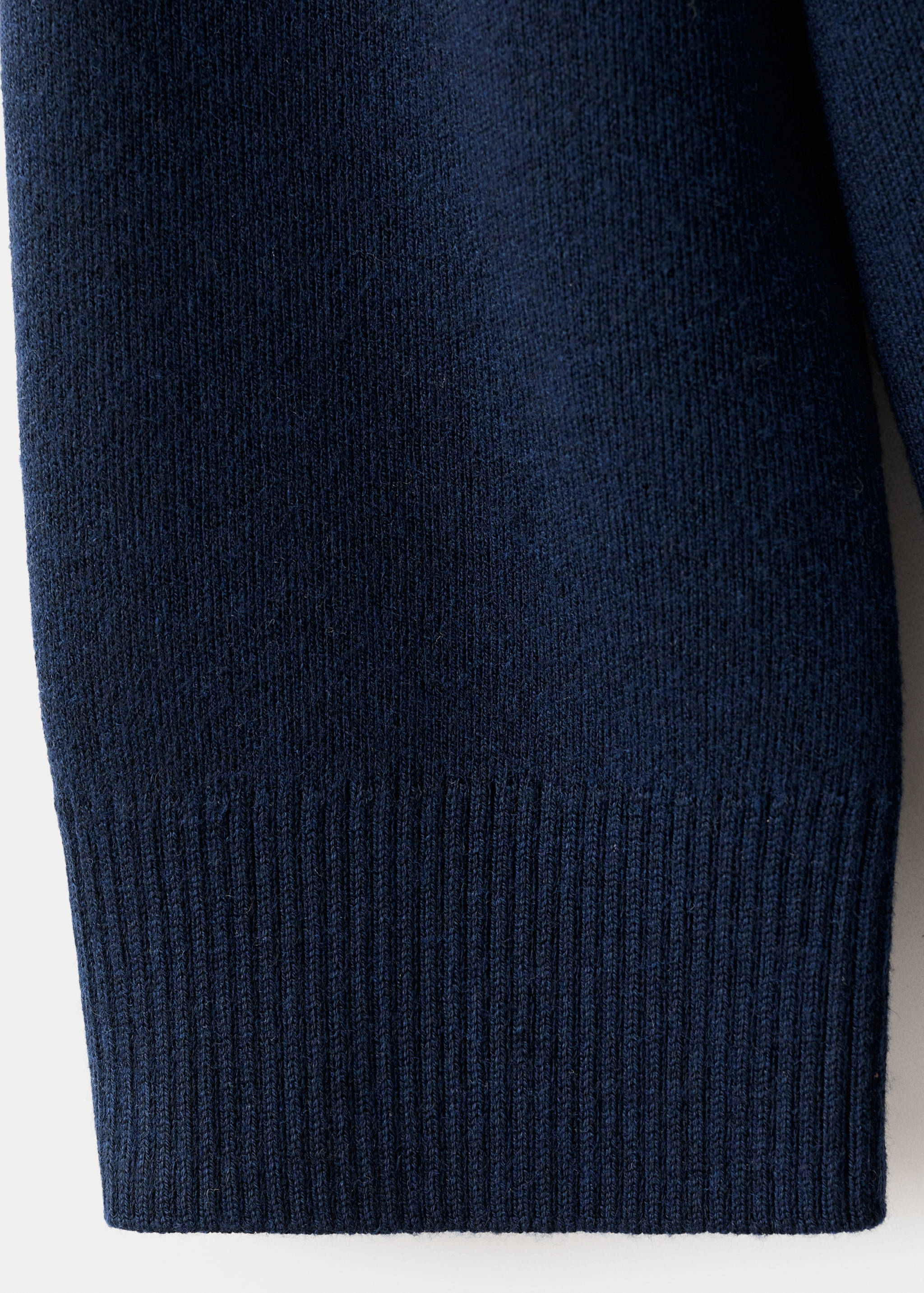 Navy blue cardigan knit fabric detail focusing on the sleeve and ribbed cuff.
