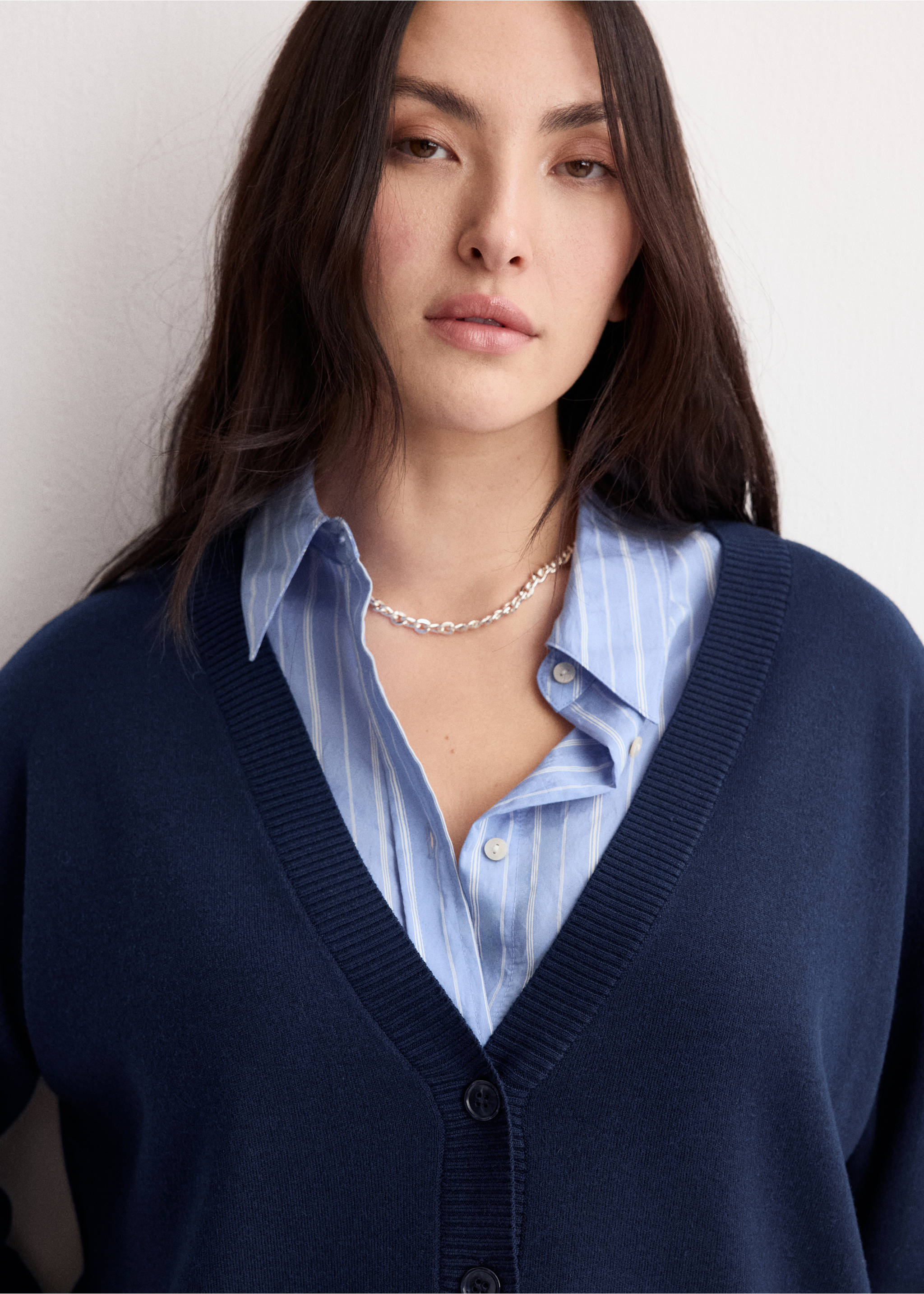 Navy blue V-neck cardigan worn over a striped shirt., Dark Navy. Ref: 27034774-00.
