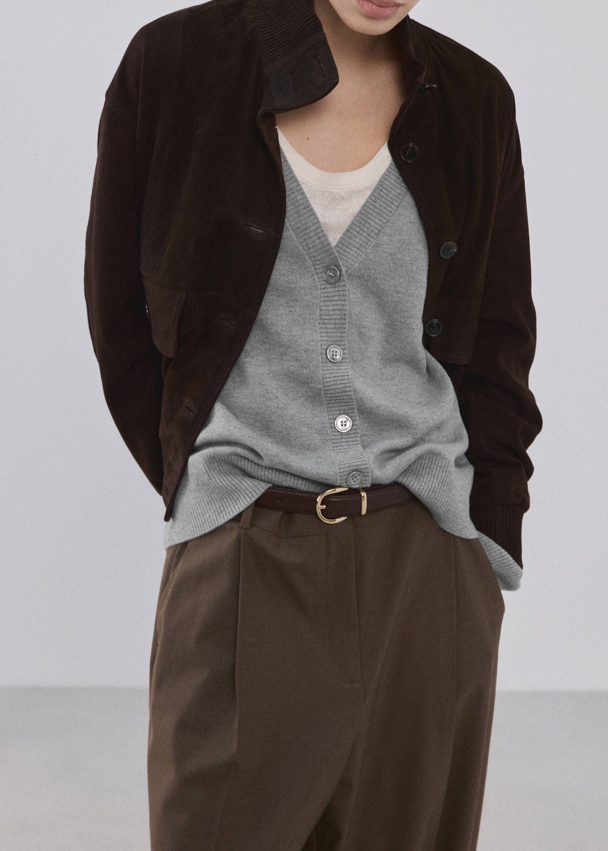 Grey V-neck button-down cardigan with ribbed trim, layered under a dark brown jacket.