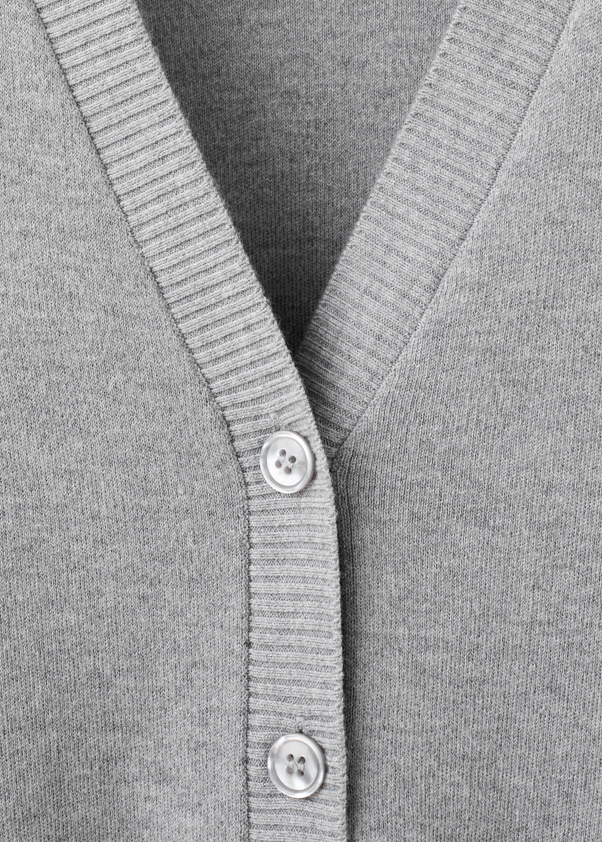 Close-up of a grey knitted cardigan featuring a V-neckline, ribbed trim and button placket.