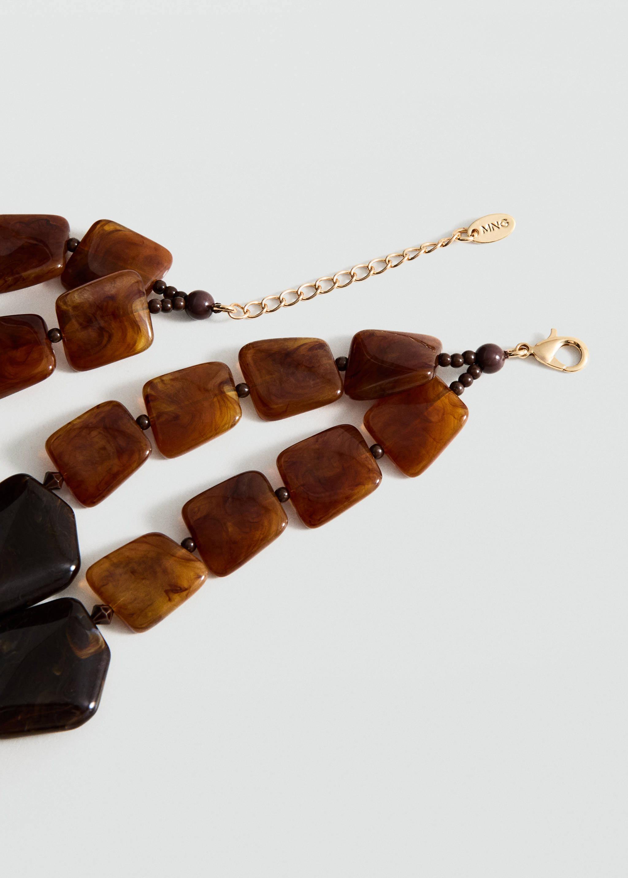 Close-up of a tortoiseshell-effect square bead necklace with a gold chain.