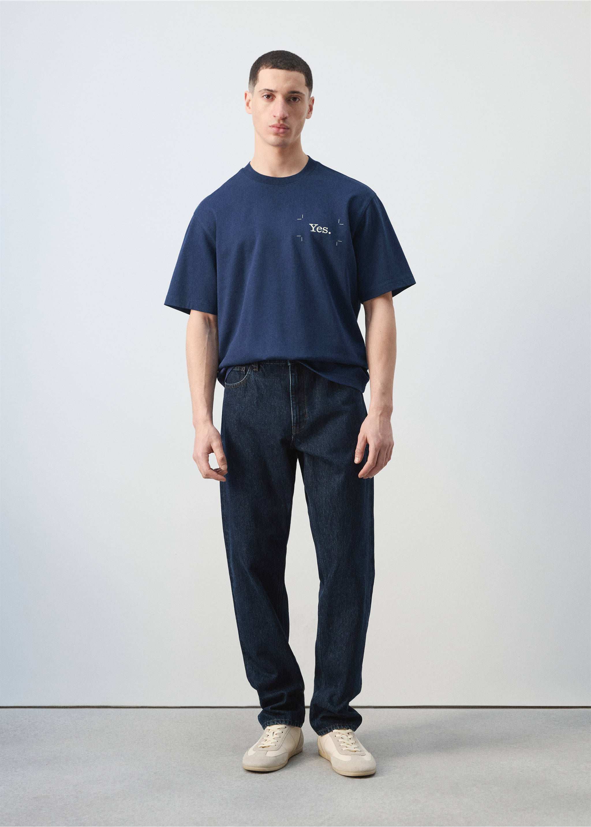 Navy blue short-sleeved t-shirt with a small white chest text print, worn with dark denim trousers., Ink Blue. Ref: 27035991-00.