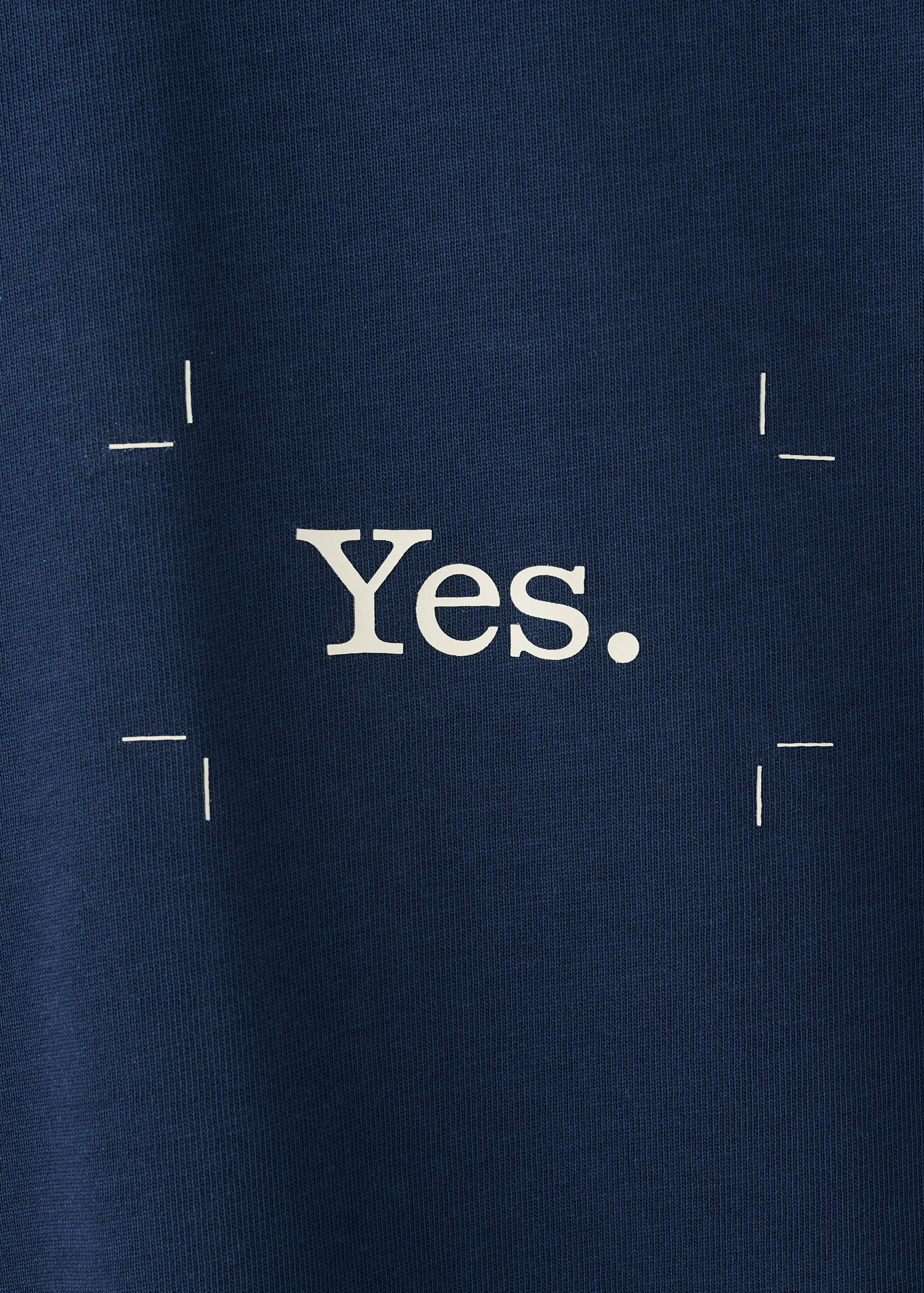 Navy blue t-shirt detail with printed white 'Yes.' text and crop marks.
