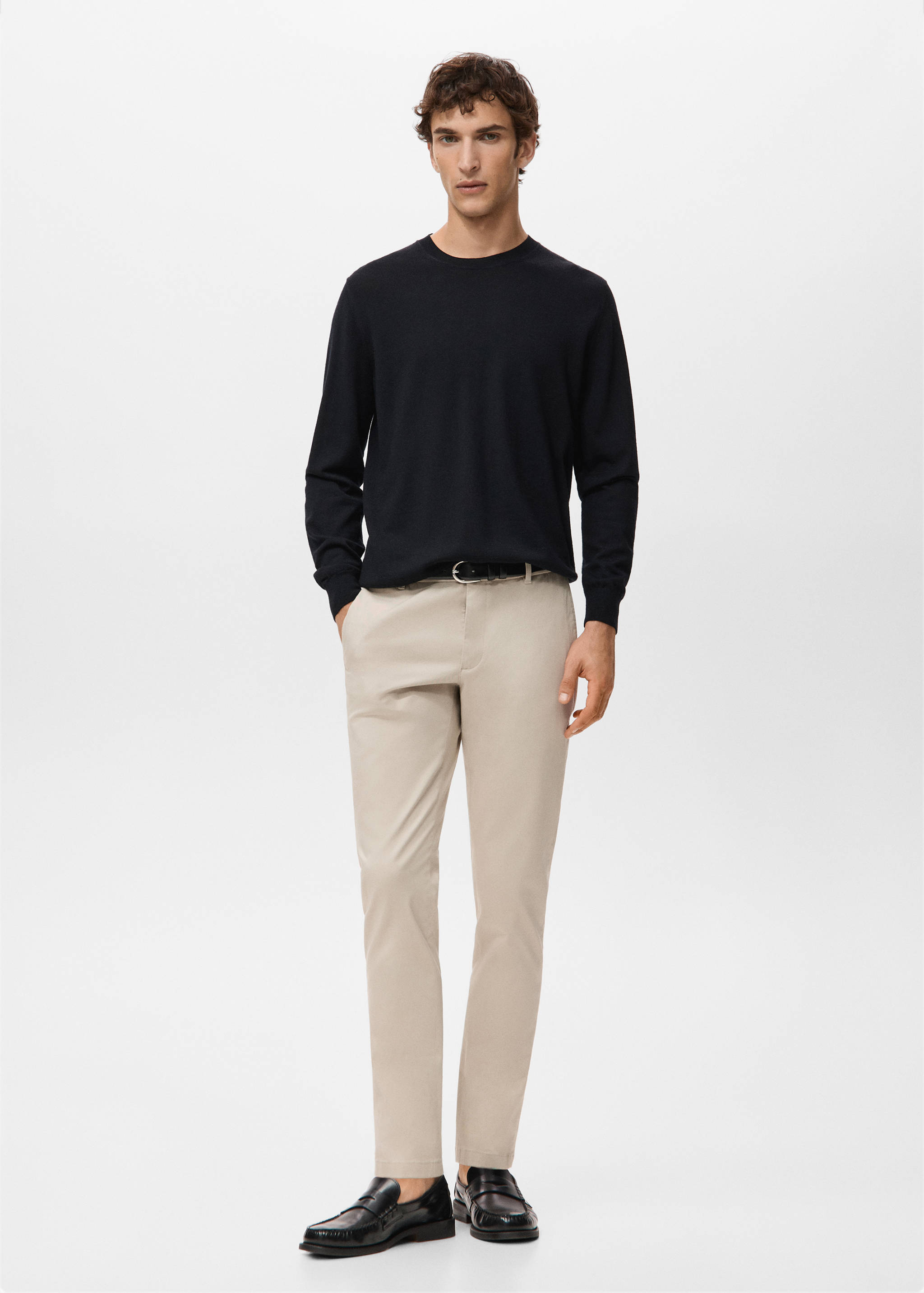 Beige trousers styled with a dark blue crew-neck sweater and black loafers.
