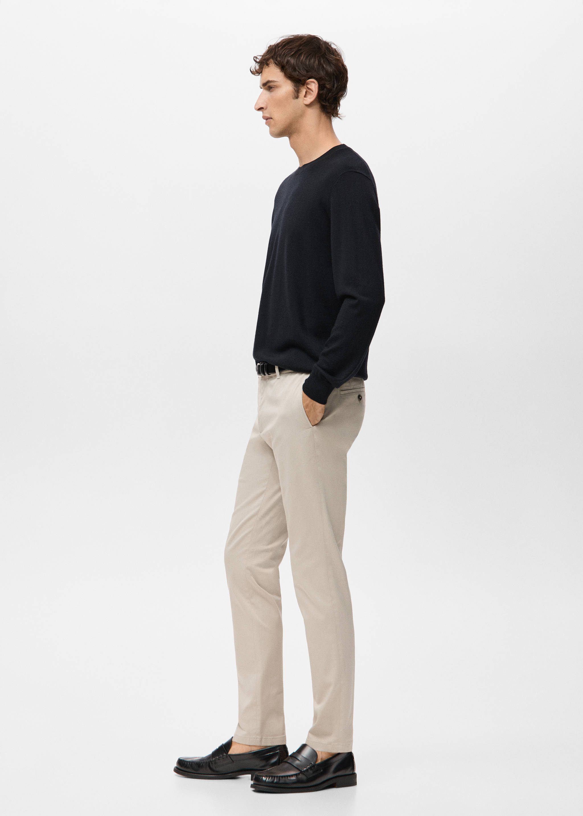 Beige trousers worn with a dark navy blue sweater and black loafers.
