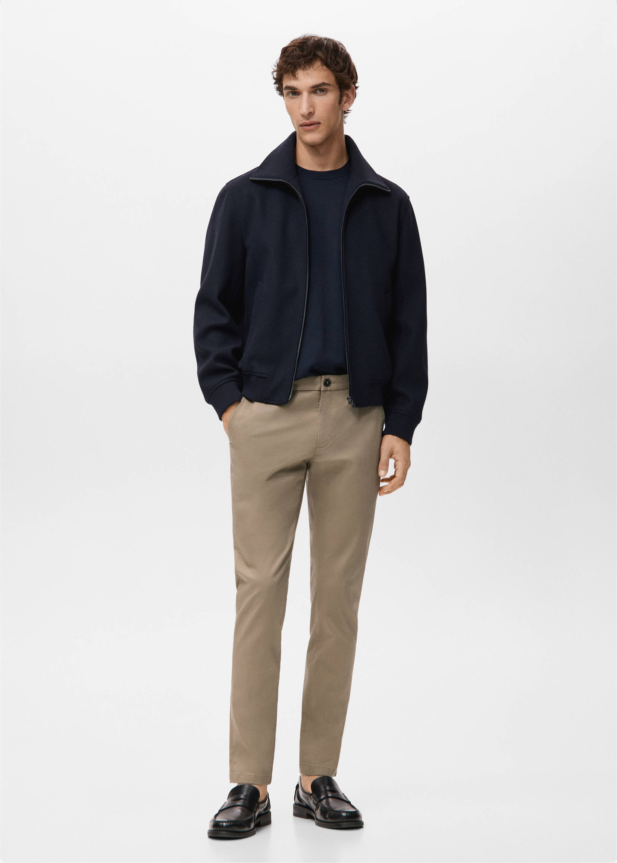 Beige trousers styled with a dark blue jacket and loafers.