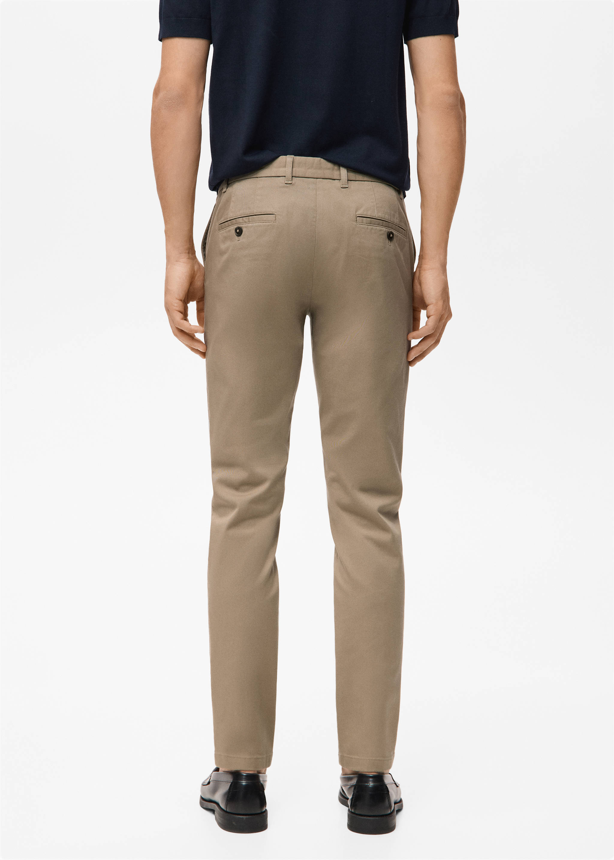 Back view of beige trousers with belt loops and buttoned rear pockets.