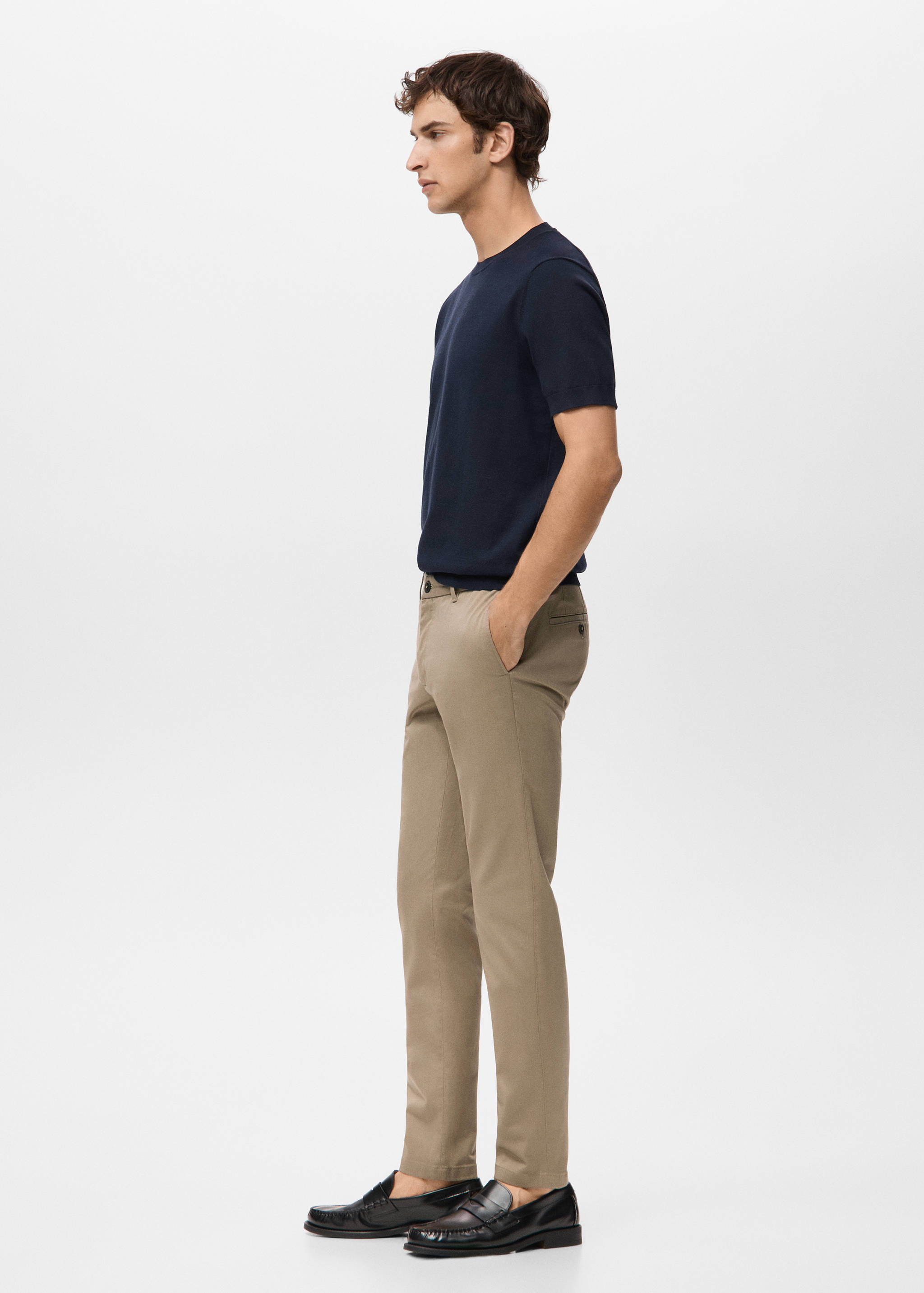 Beige trousers with a straight-leg fit, worn with a navy t-shirt and loafers.