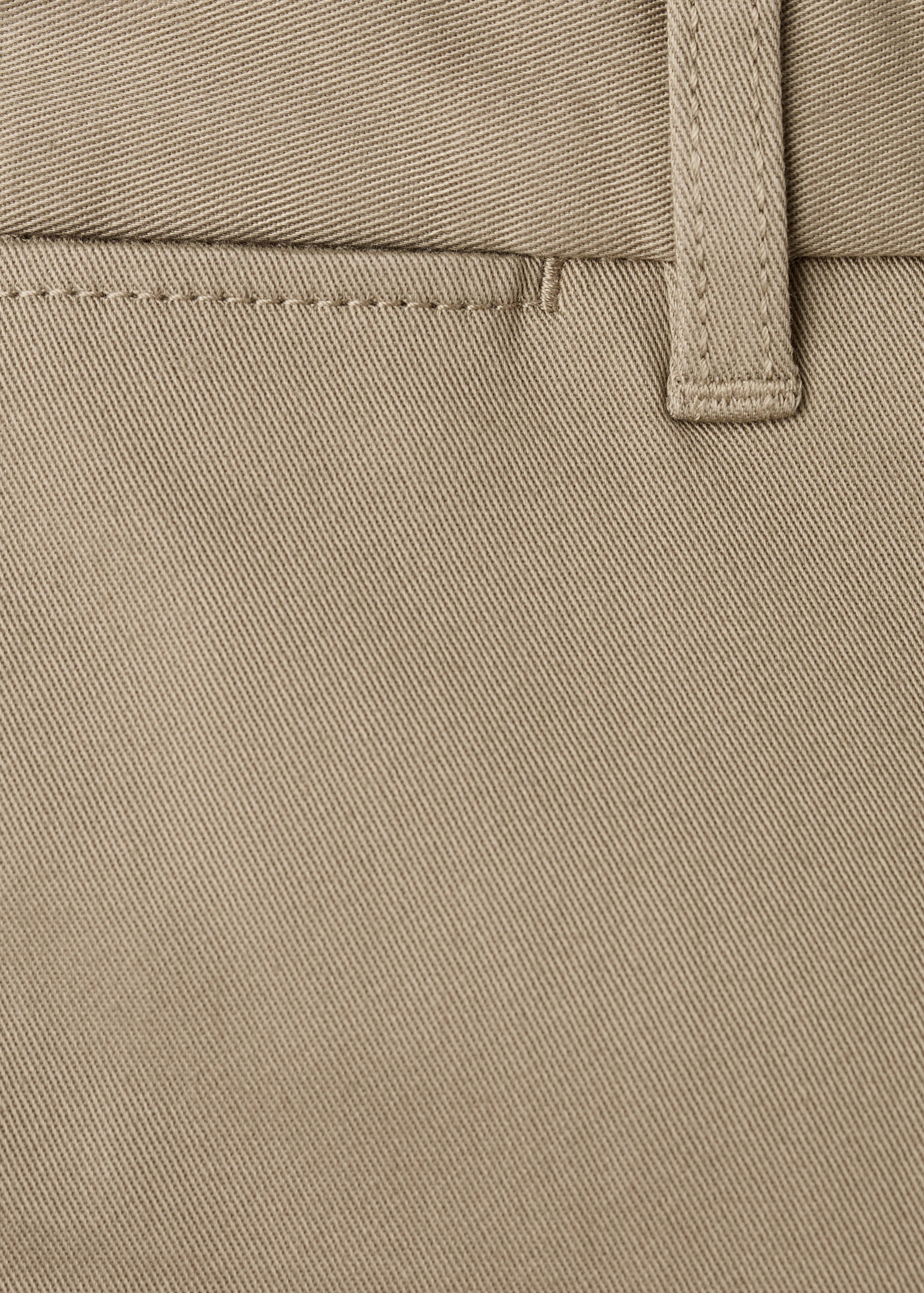 Close-up of beige trousers fabric texture and belt loop.