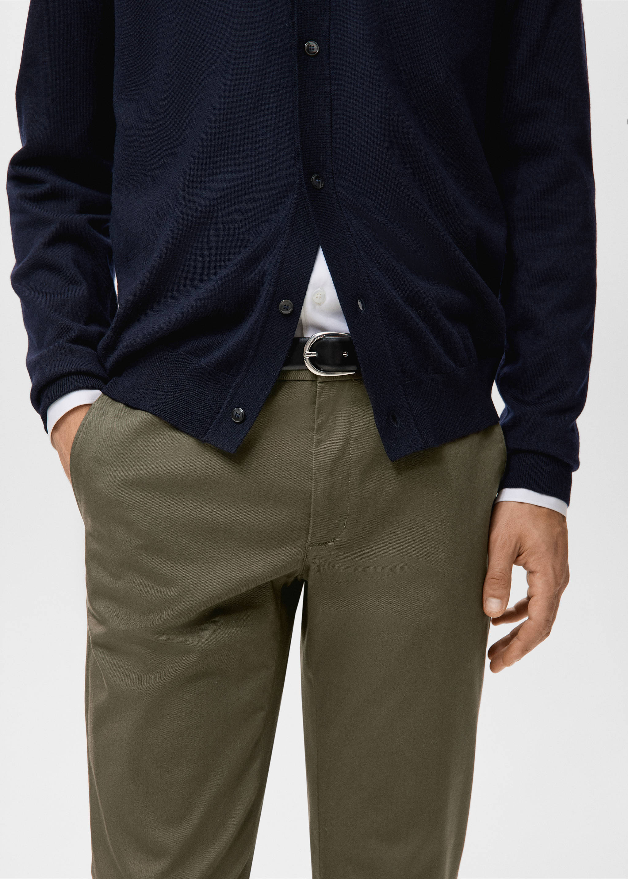 Dark olive green trousers paired with a black belt and navy cardigan.