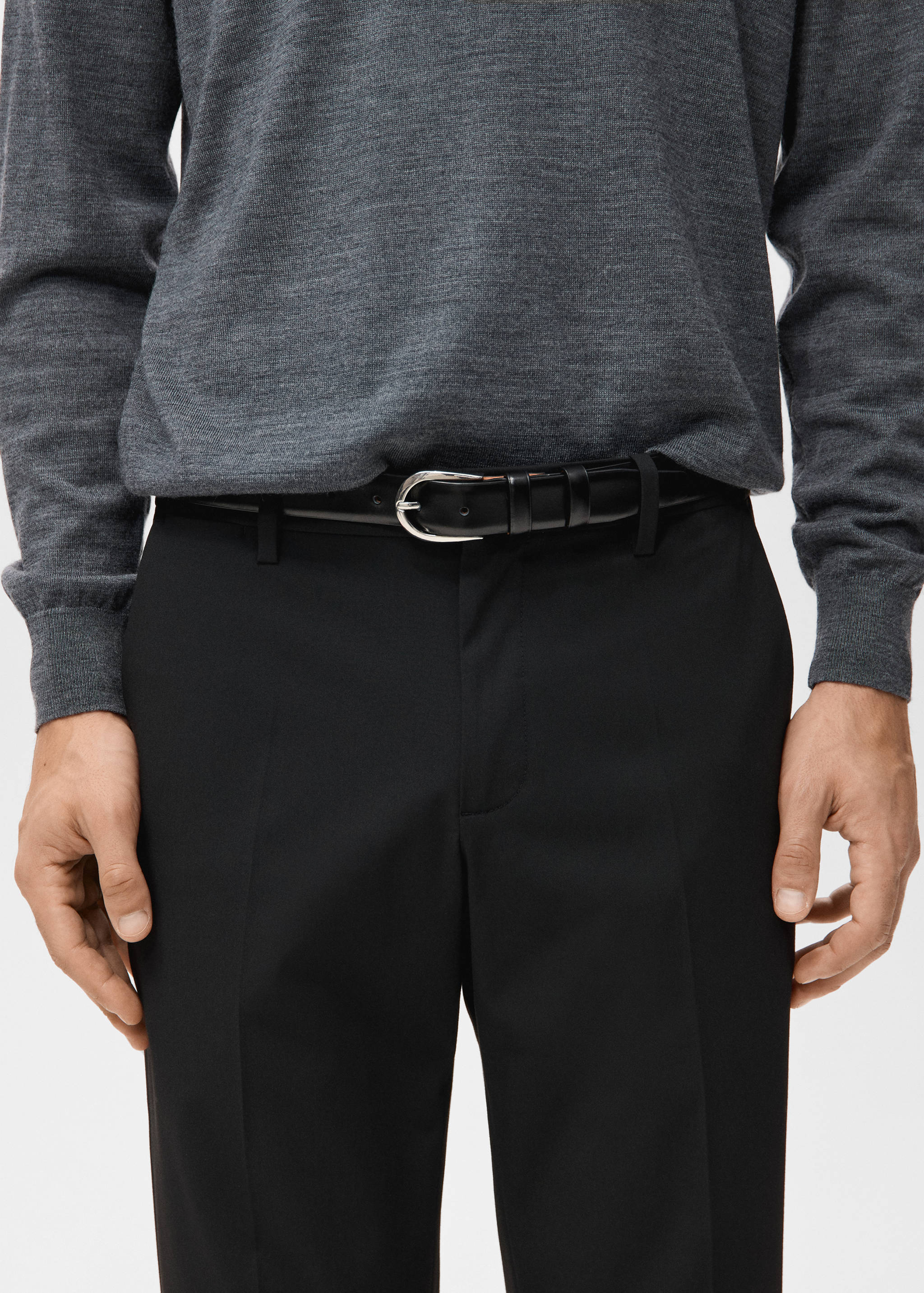 Black trousers worn with a black leather belt and grey sweater.