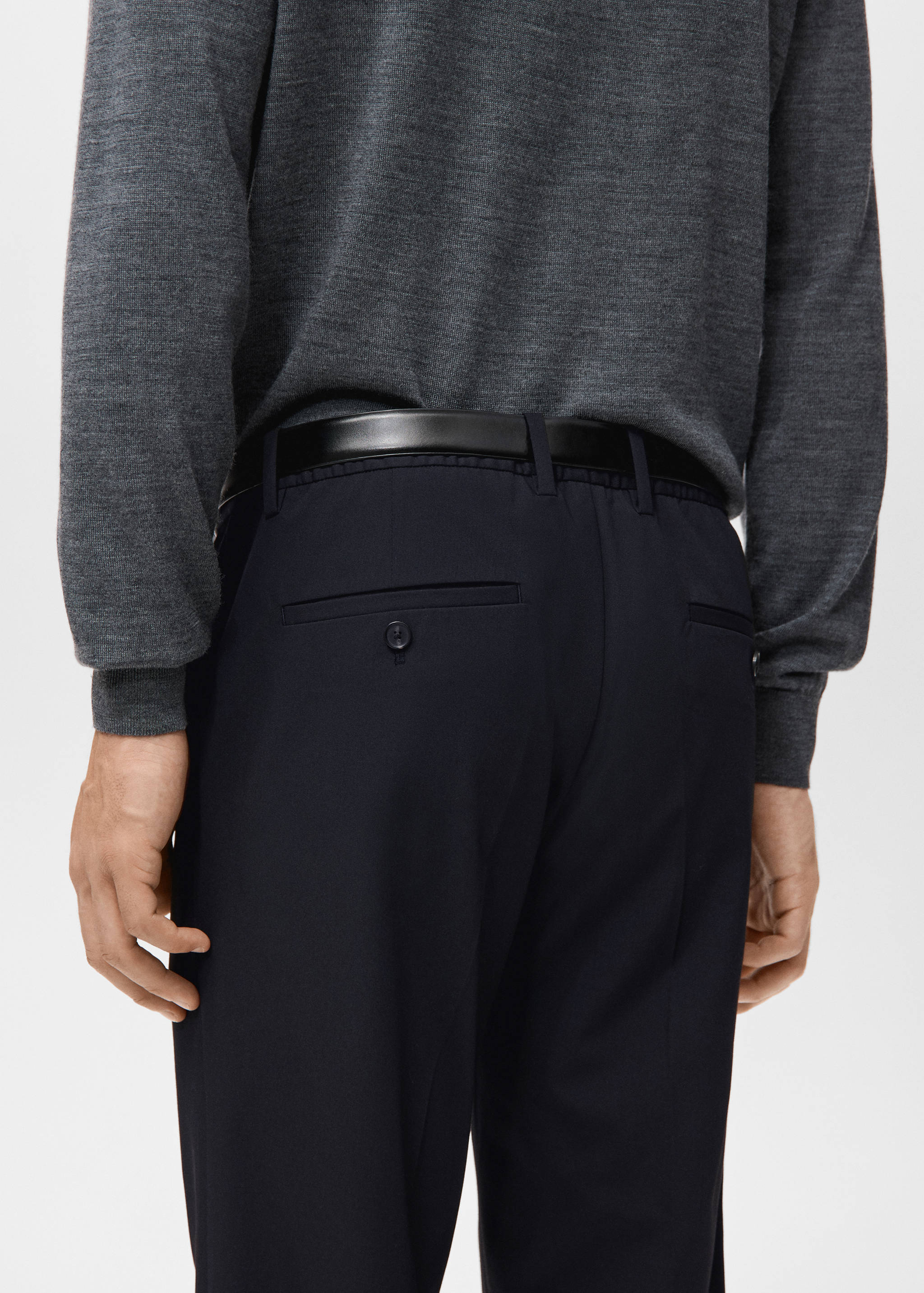 Navy blue trousers from behind, paired with a black belt and grey sweater.