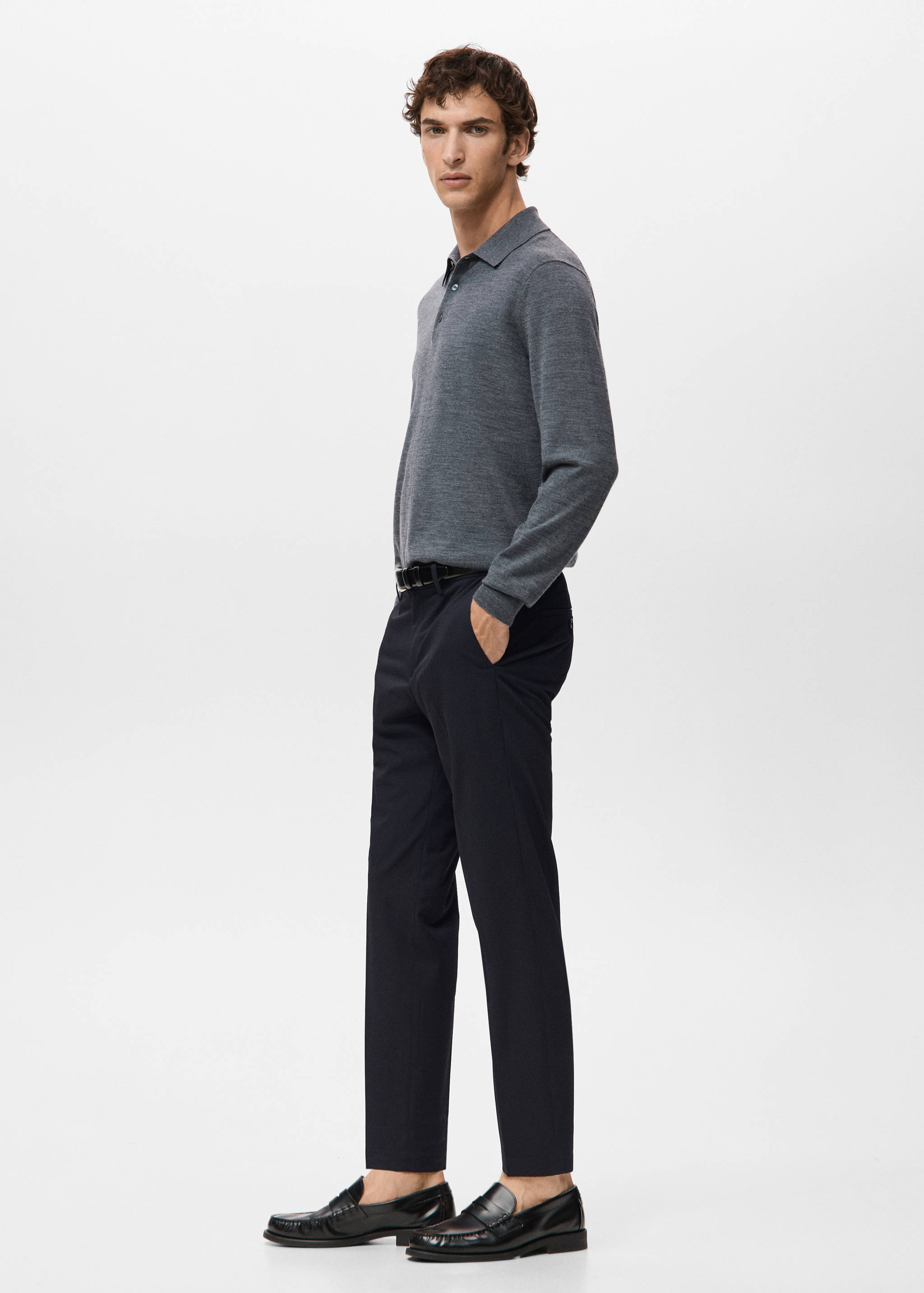 Navy blue trousers in a straight fit paired with a grey polo sweater.