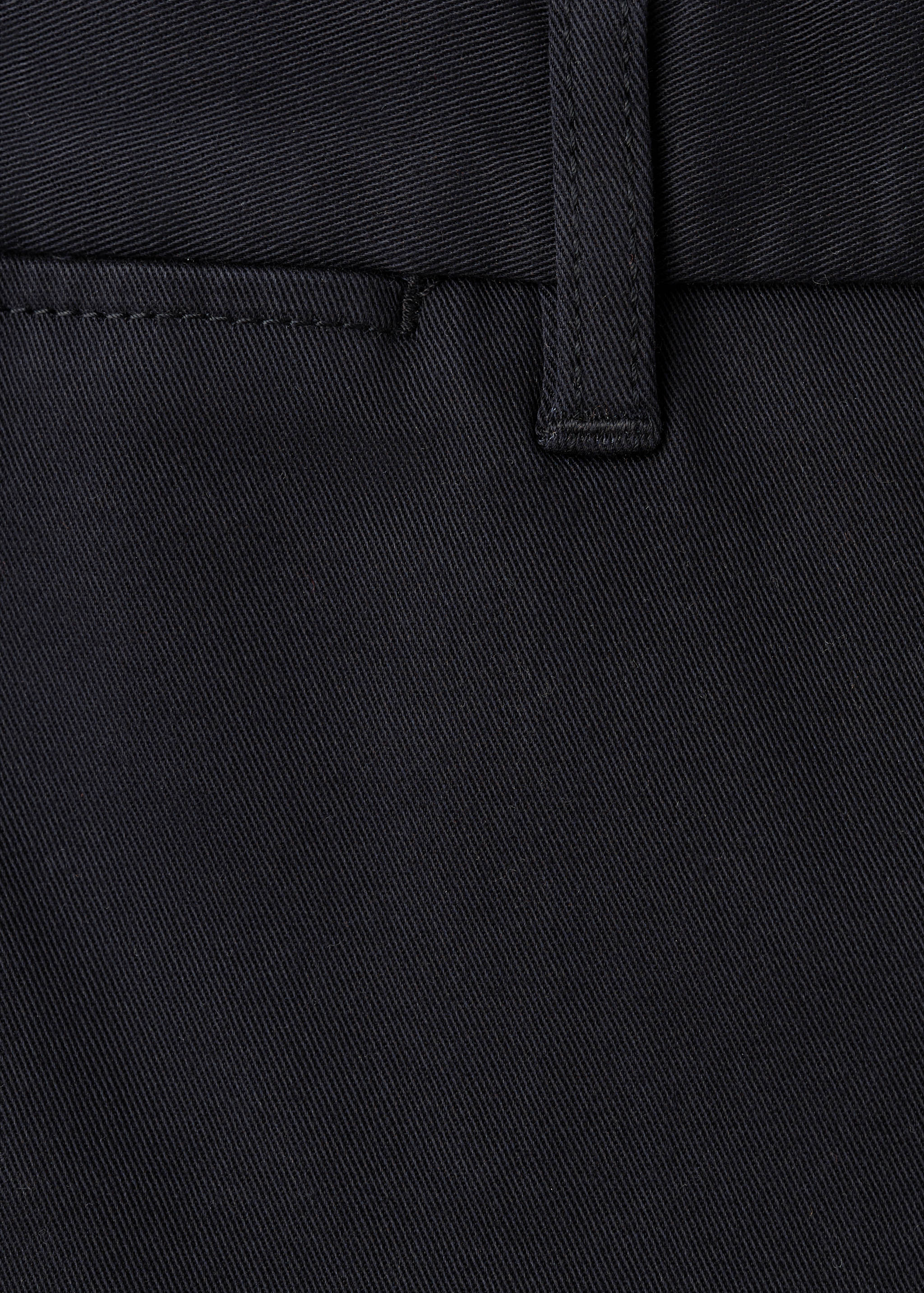 Close-up of black trousers showing the waistband detail and belt loop.