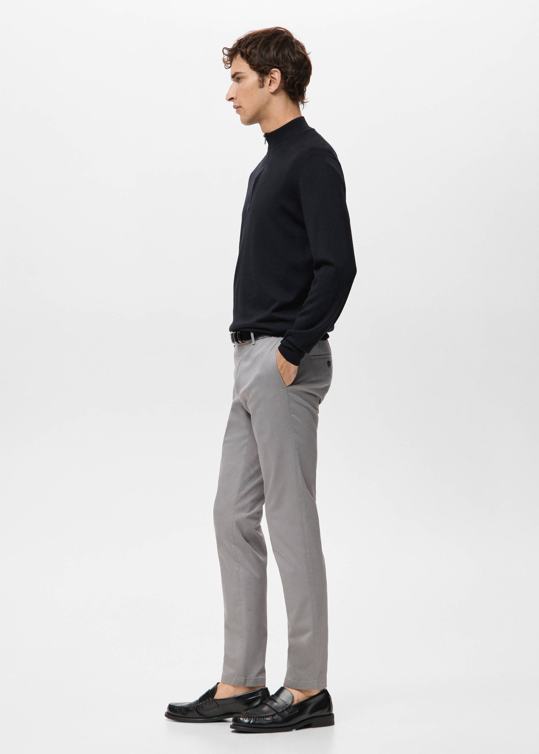 Grey slim-fit trousers worn with a black half-zip sweater.