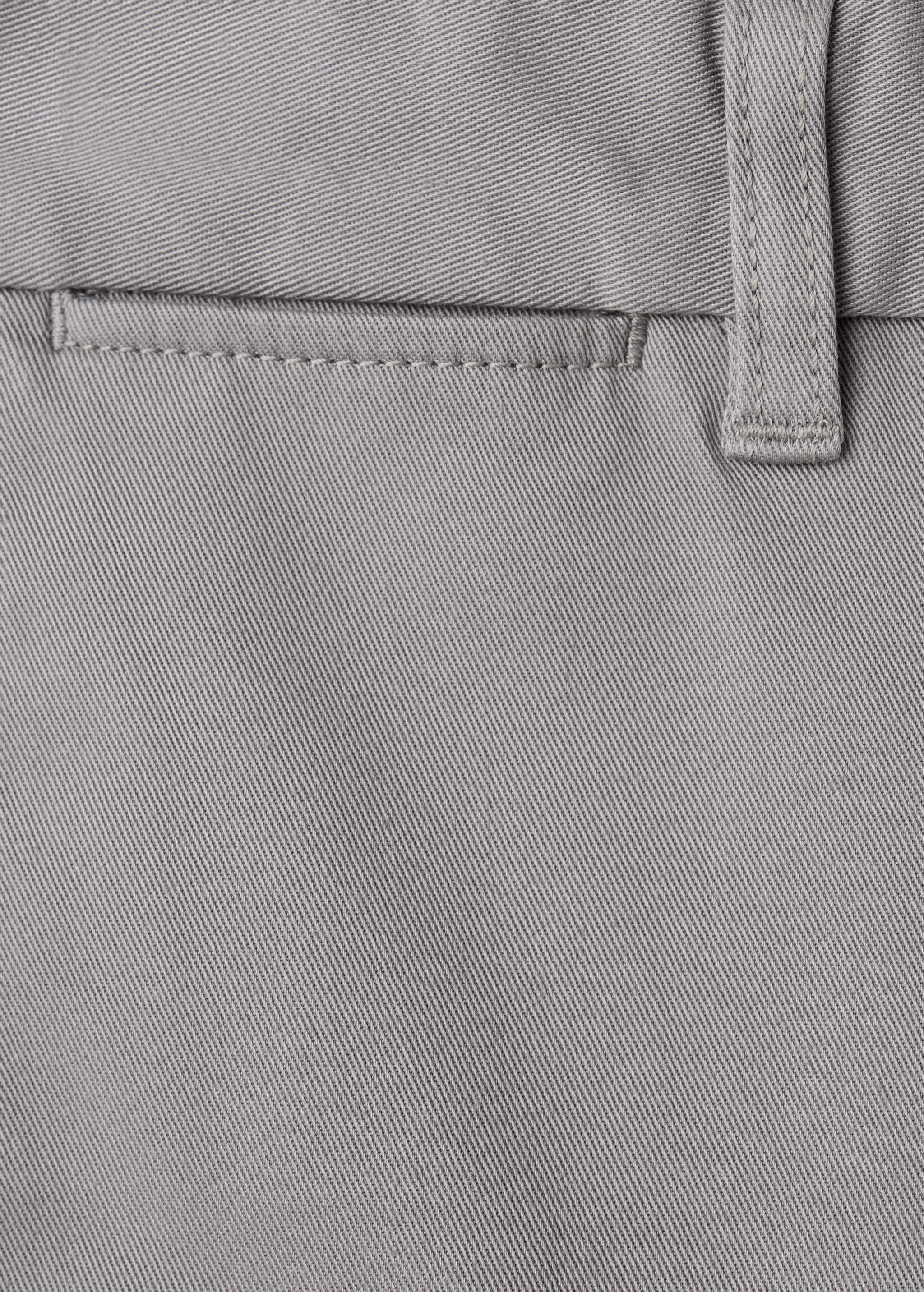 Close-up of grey trousers showing the twill fabric texture and belt loop detail.