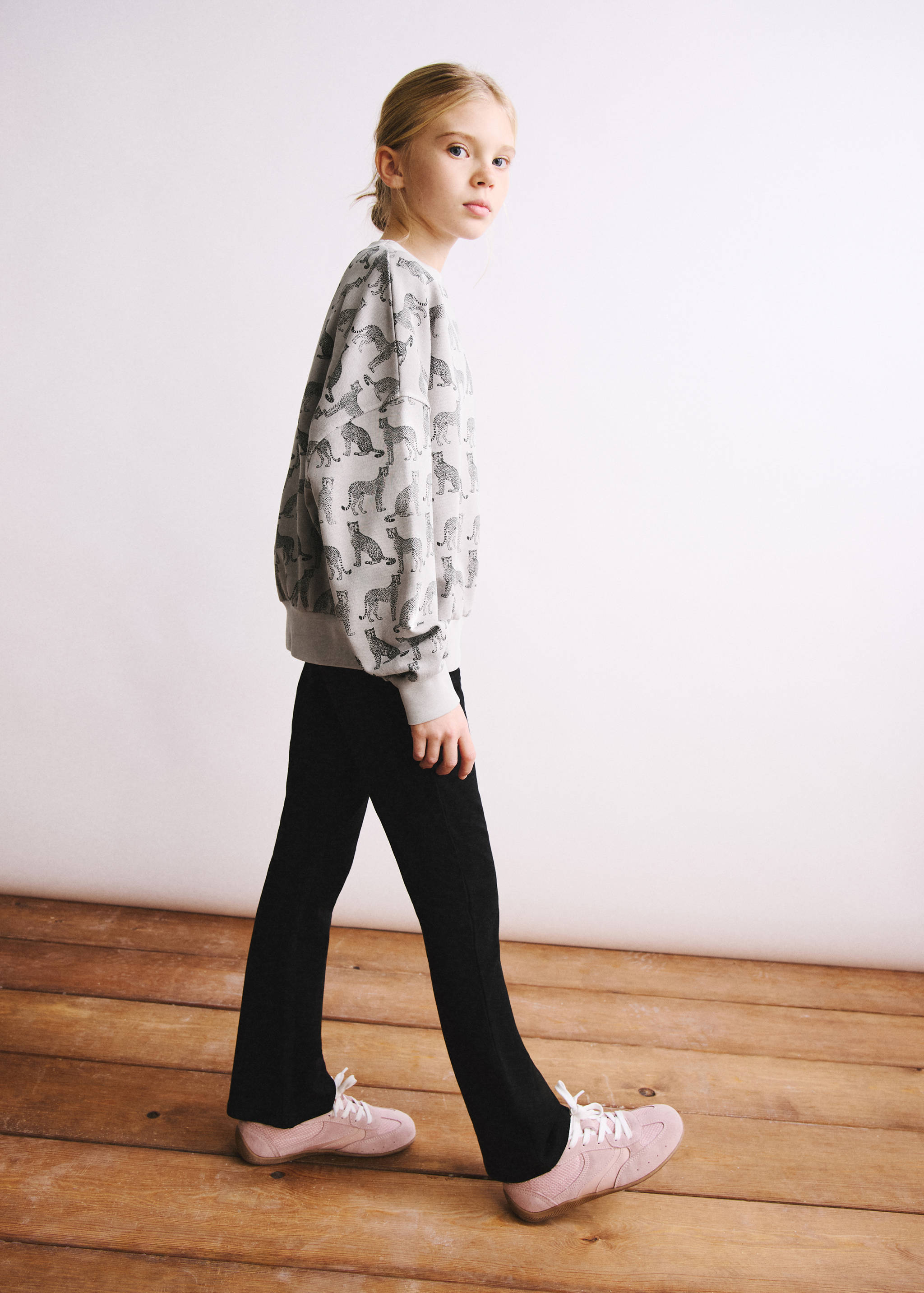 Black leggings styled with a patterned grey sweatshirt and pink trainers.