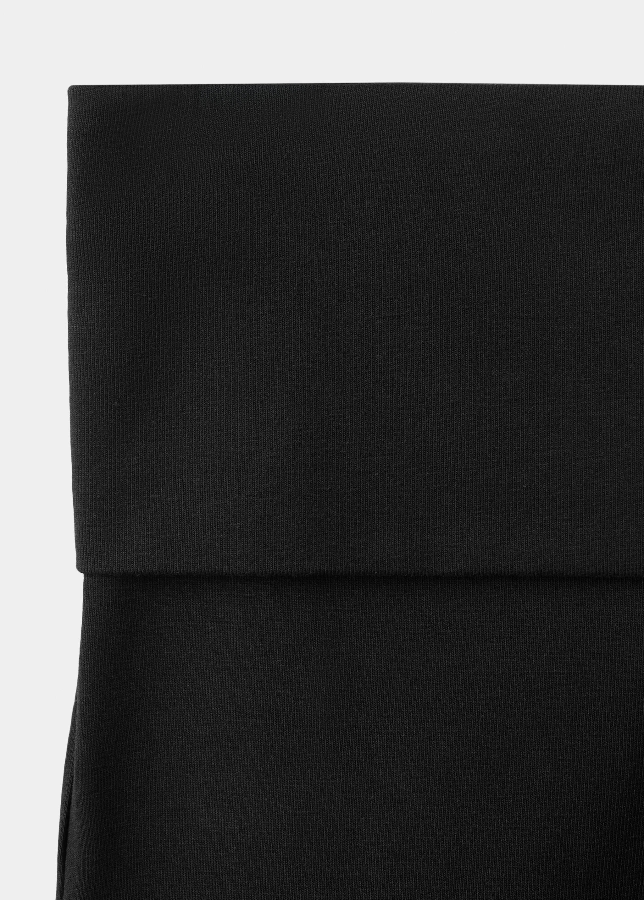 Black leggings with a wide fold-over waistband, close-up.