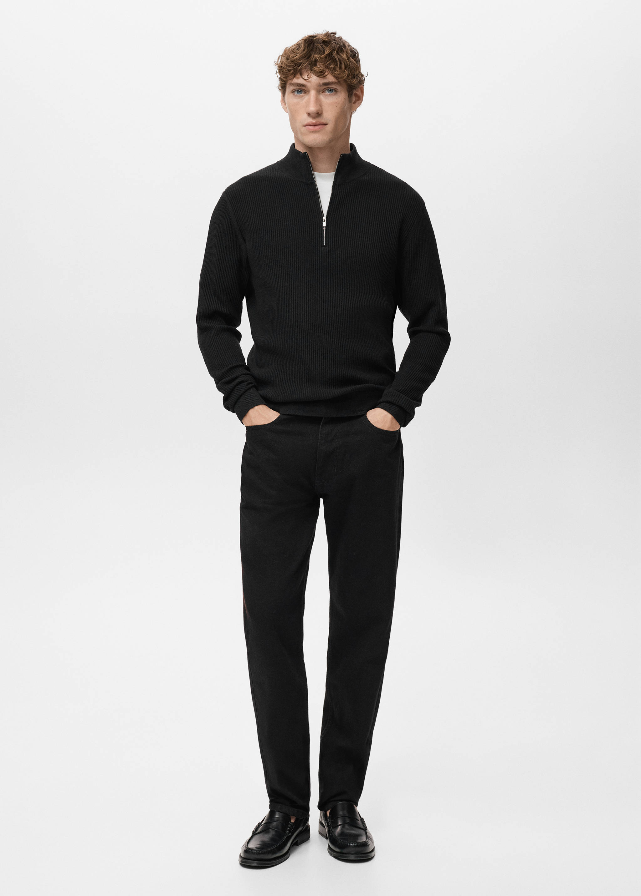 Black ribbed half-zip jersey worn with black trousers.