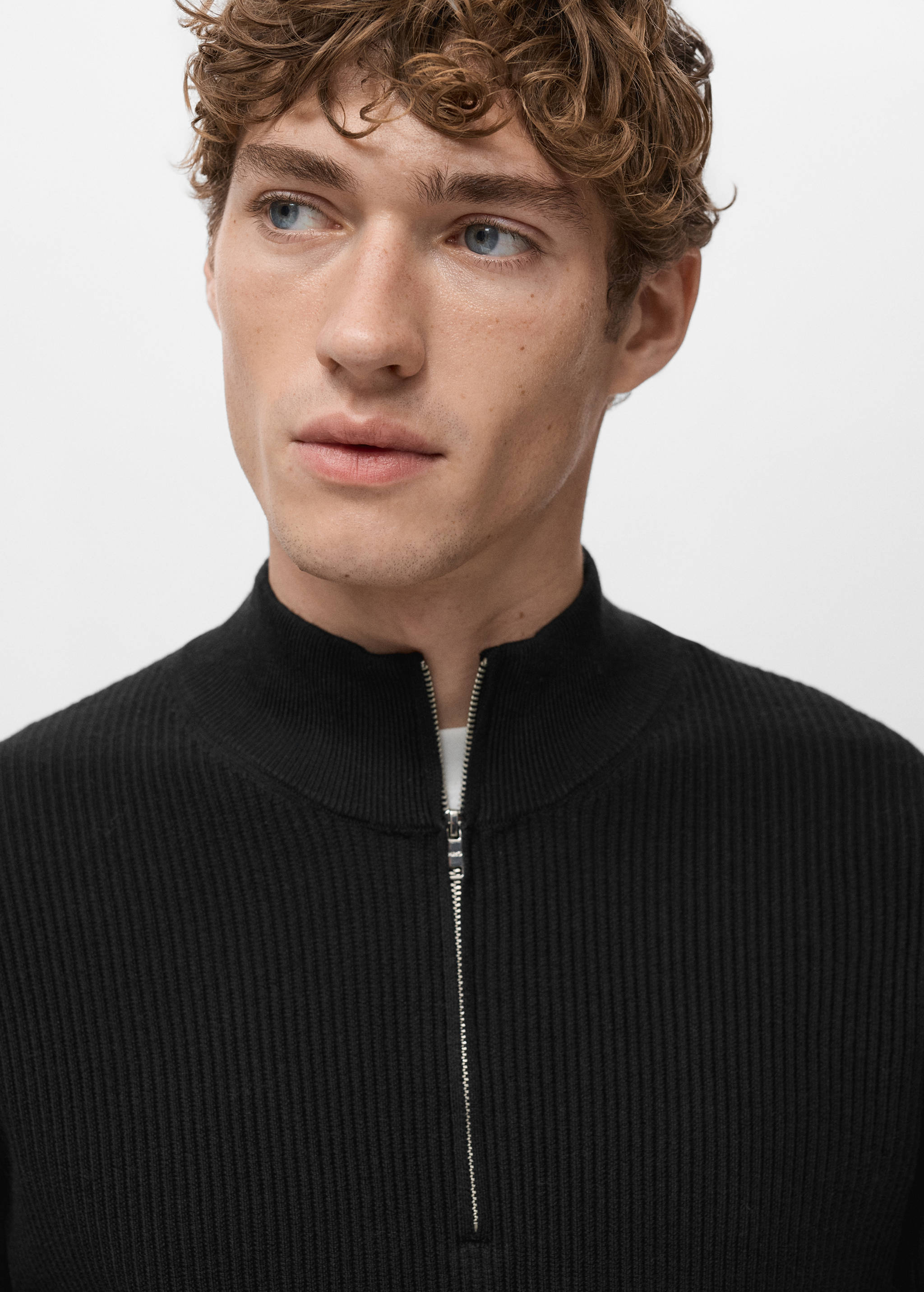 Black ribbed jumper with a high neck and a silver half-zip.