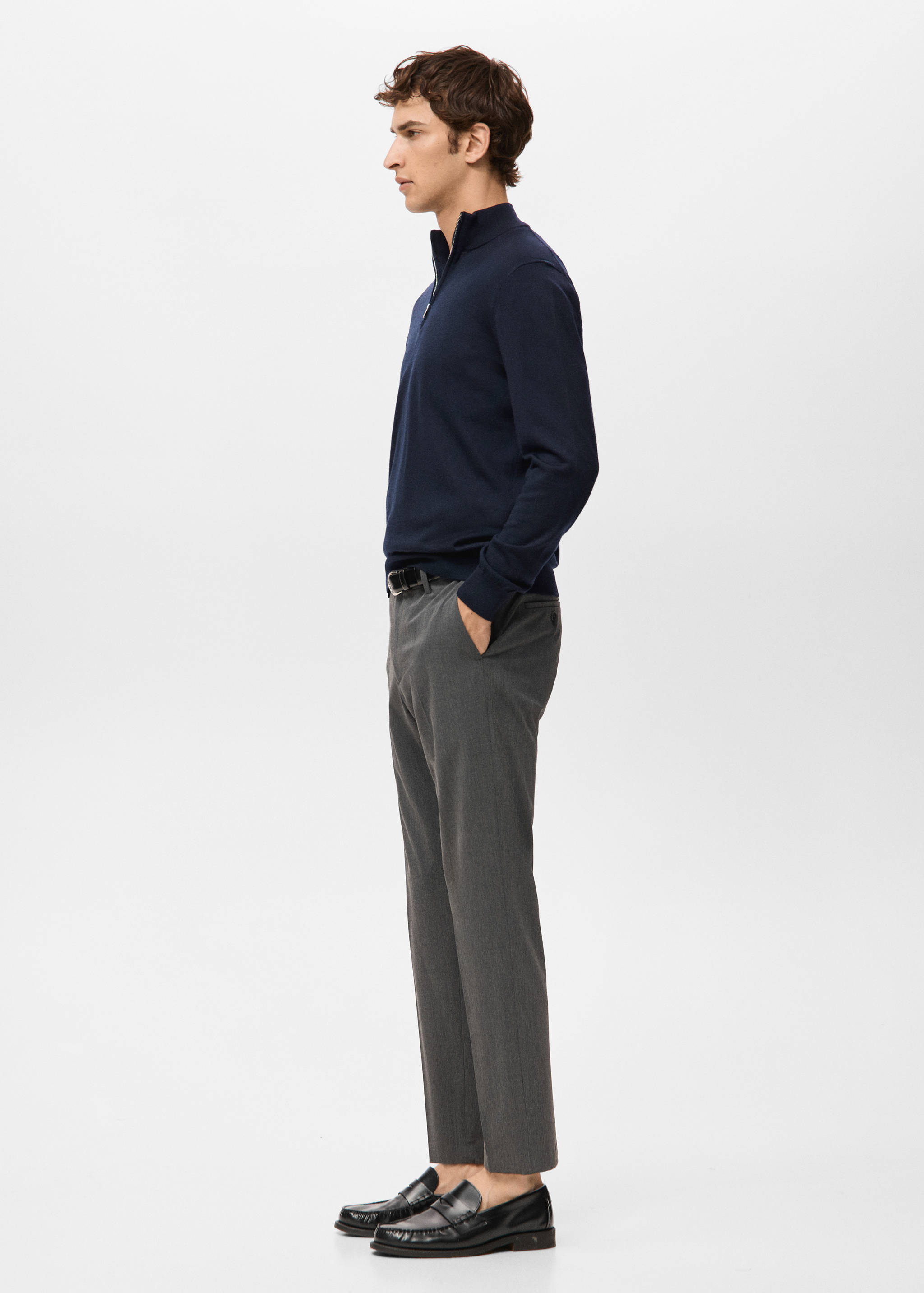 Navy blue zip-neck jersey with long sleeves worn with grey trousers.