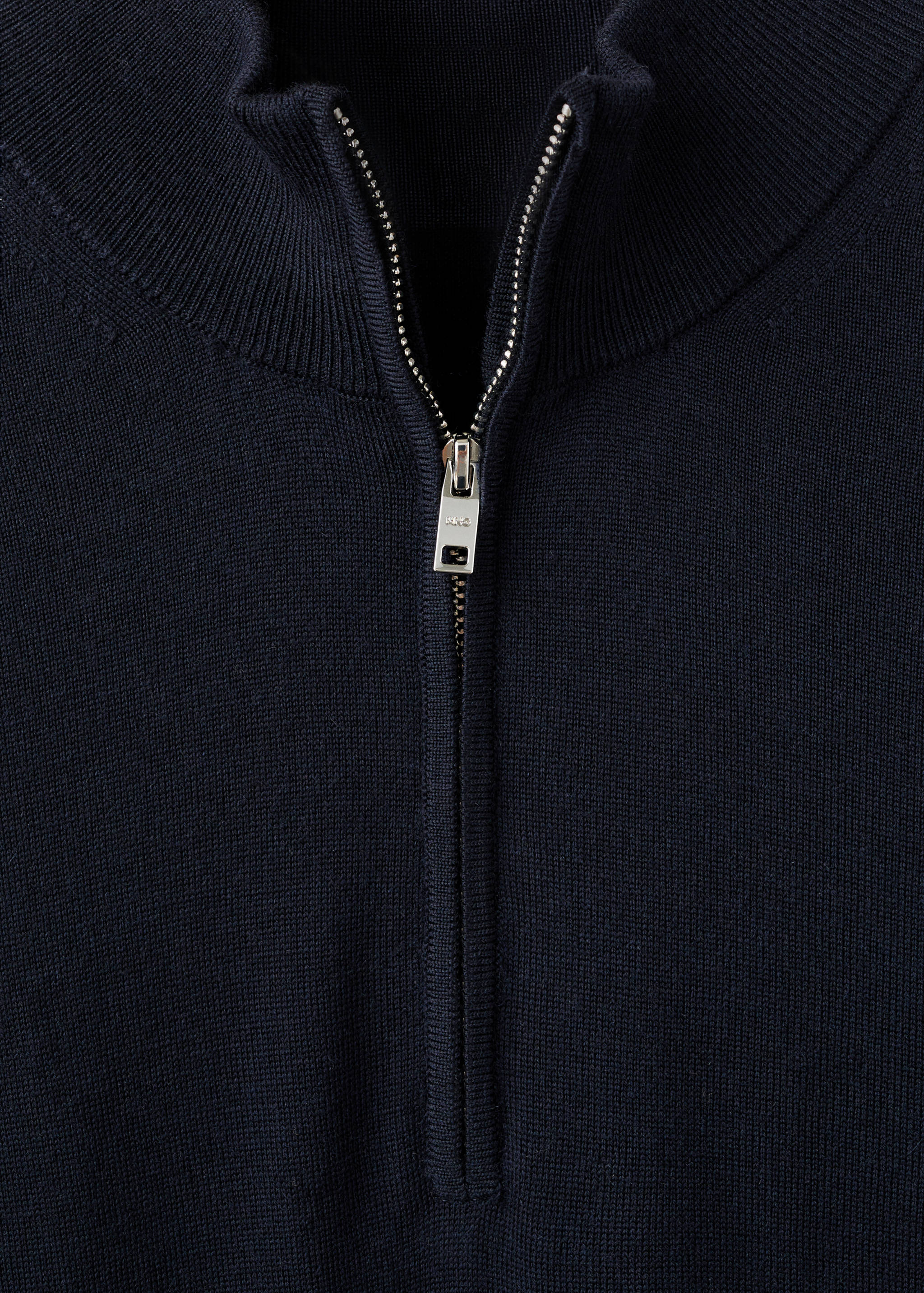 Close-up of the half-zip neck and silver zipper on a dark navy blue jersey.