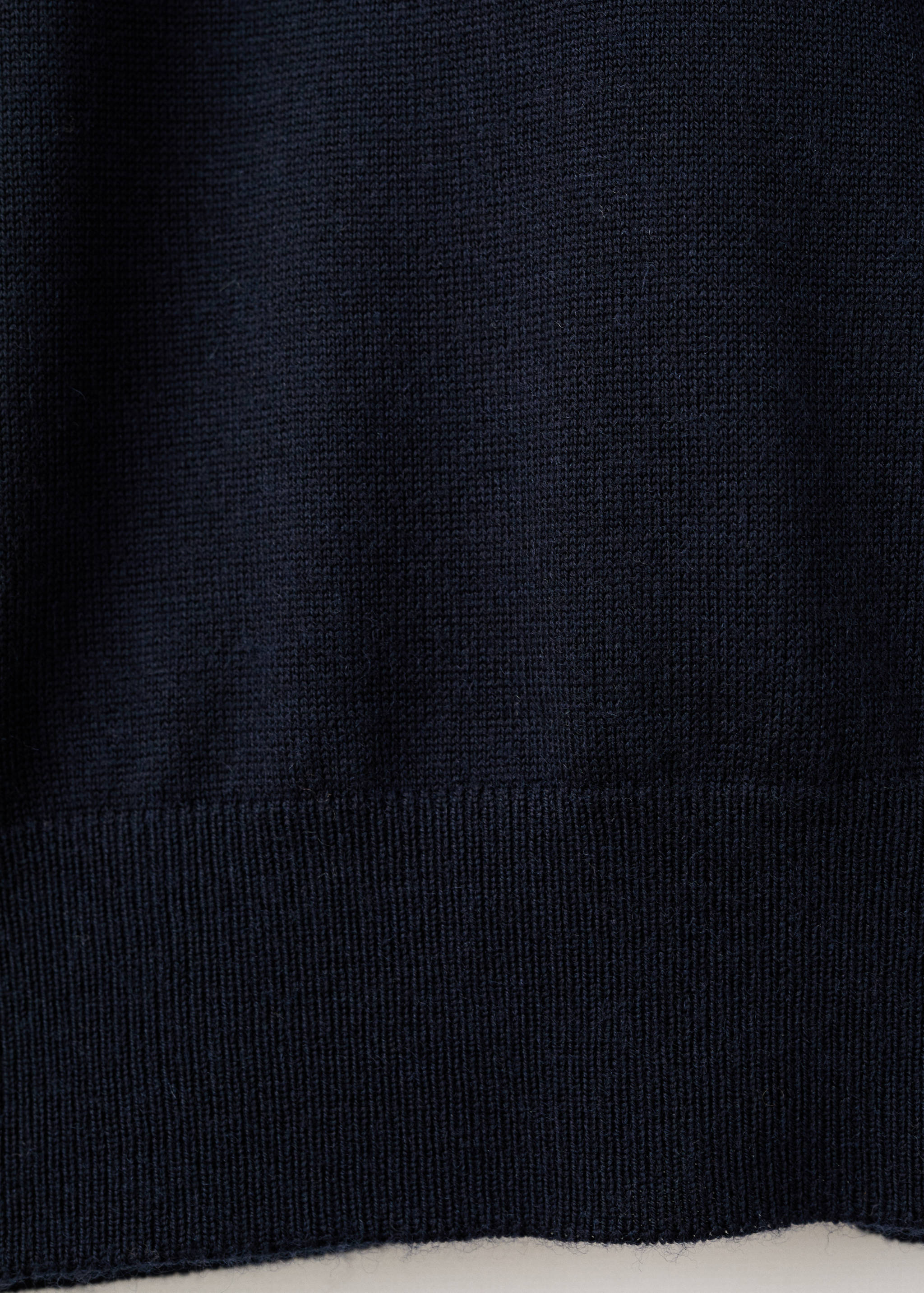 Close-up of a dark navy blue fine-knit jersey showing the knit texture and ribbed hem.