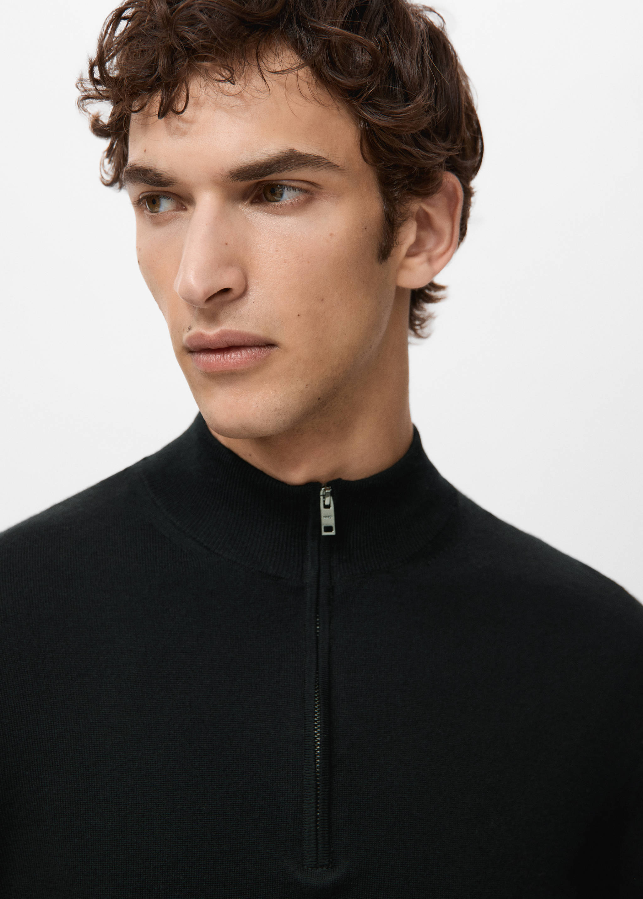 Black knitted jersey with a high zip-up collar, shown in close-up.